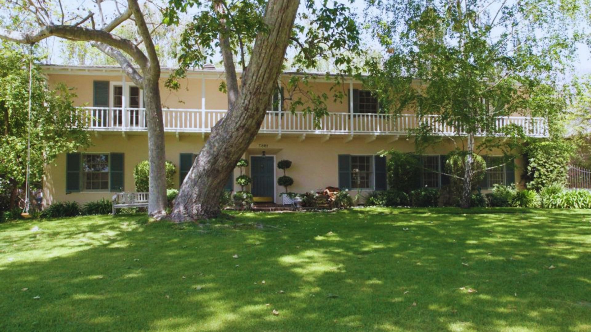 A large house surrounded by a spacious yard and several trees, showcasing a serene outdoor environment.