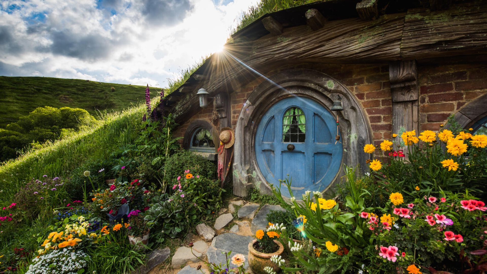 A charming hobbit house nestled among vibrant flowers in a lush garden setting.