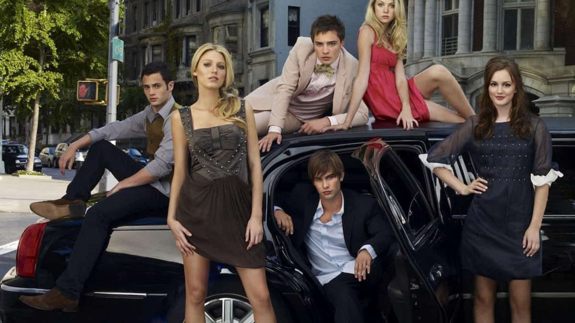 The cast of Gossip Girl poses together in front of a limousine, showcasing their stylish outfits and camaraderie.