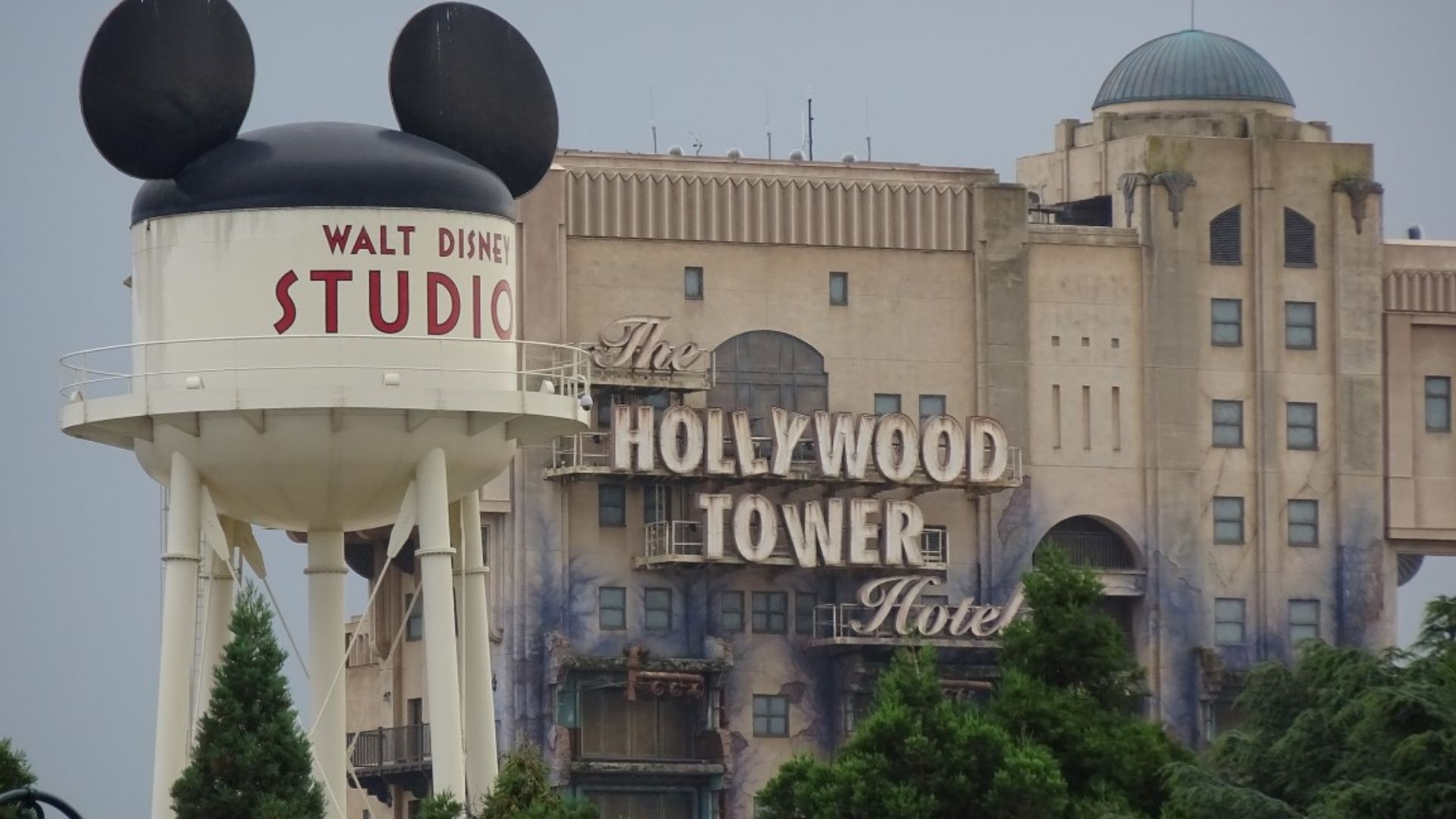 The Hollywood Tower Hotel at Disneyland, a tall, eerie building with a vintage design, surrounded by lush greenery.