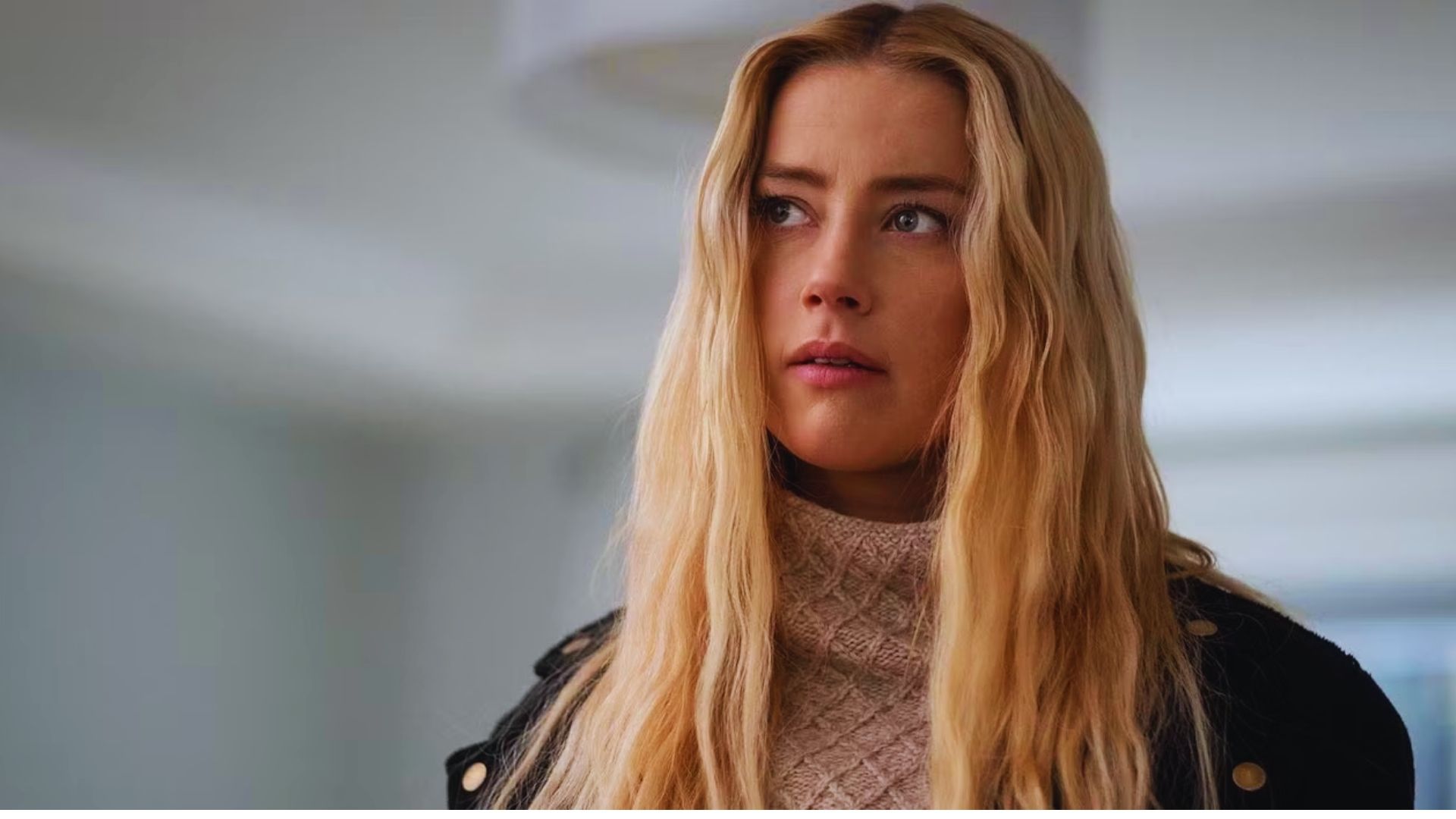A close-up of Amber Heard portraying Nadine Cross, her long blonde hair flowing as she looks off to the side in The Stand (2020).