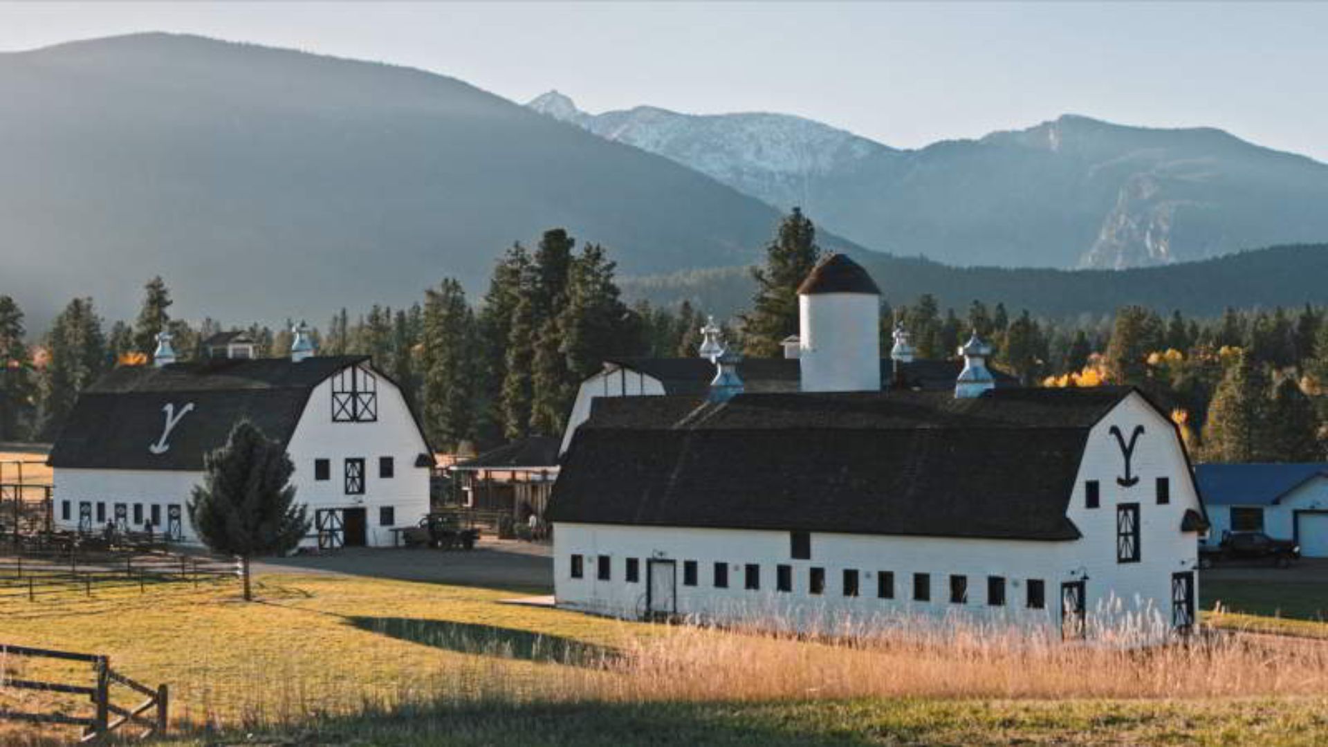 The rustic barns at a British Columbia ranch, surrounded by lush greenery and mountains in the background.
