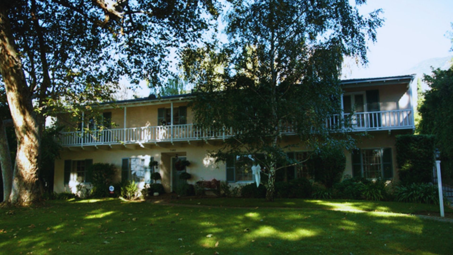 A large house surrounded by a spacious yard and several trees, showcasing a serene outdoor environment.