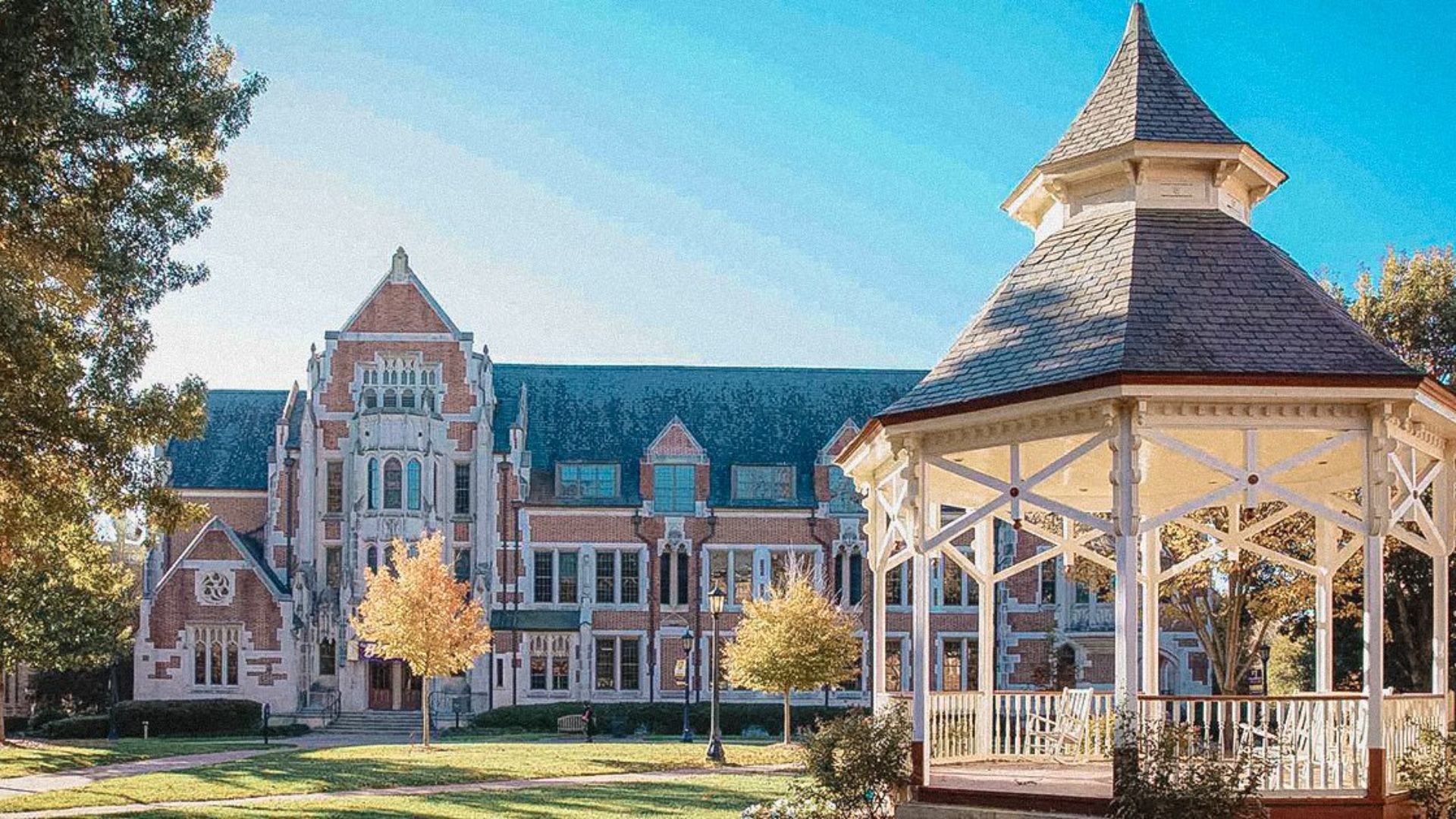 A gazebo stands in front of a building featuring a prominent clock tower.