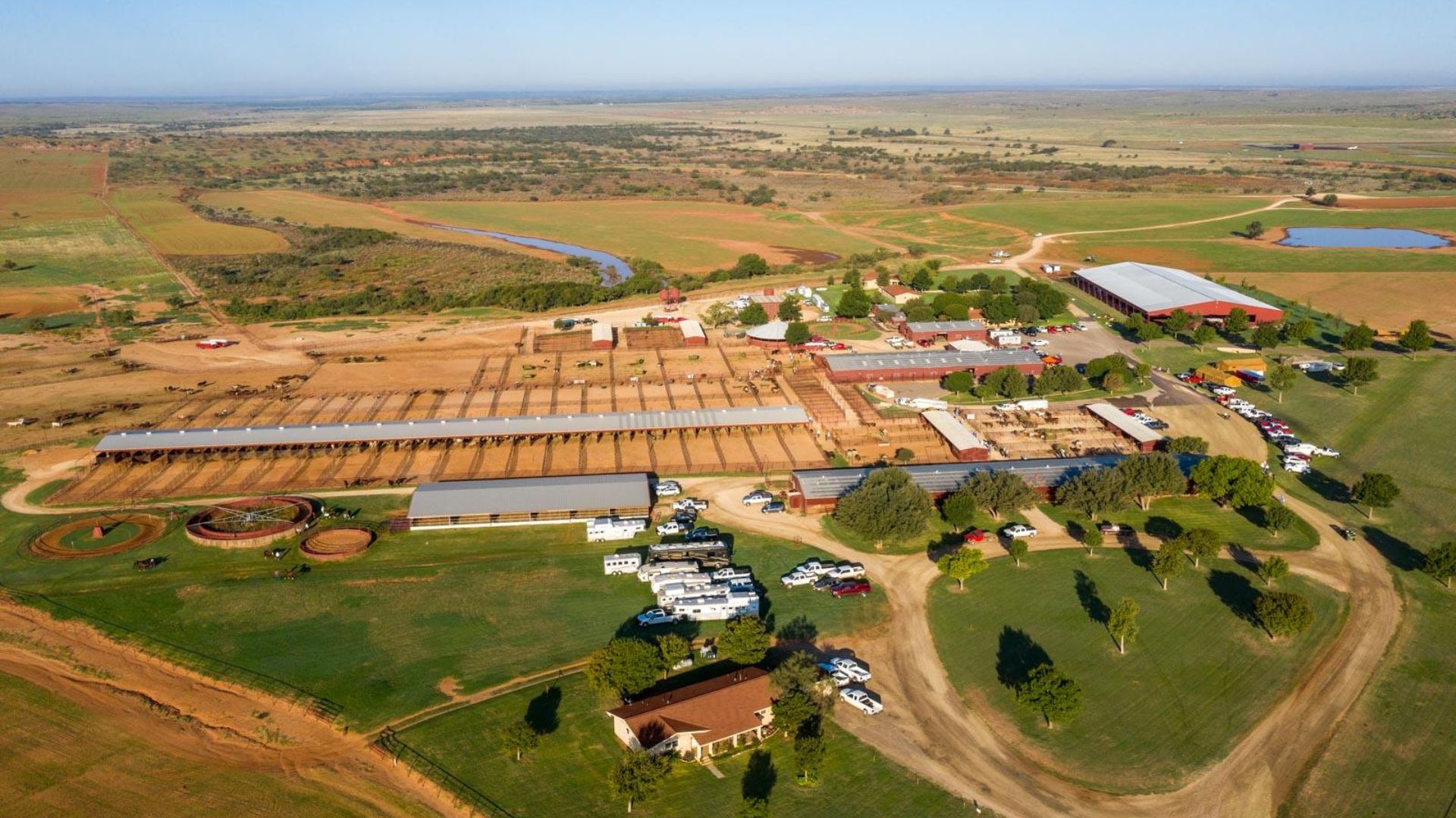 Aerial view of a farm featuring a red barn and a white farmhouse surrounded by fields and greenery.