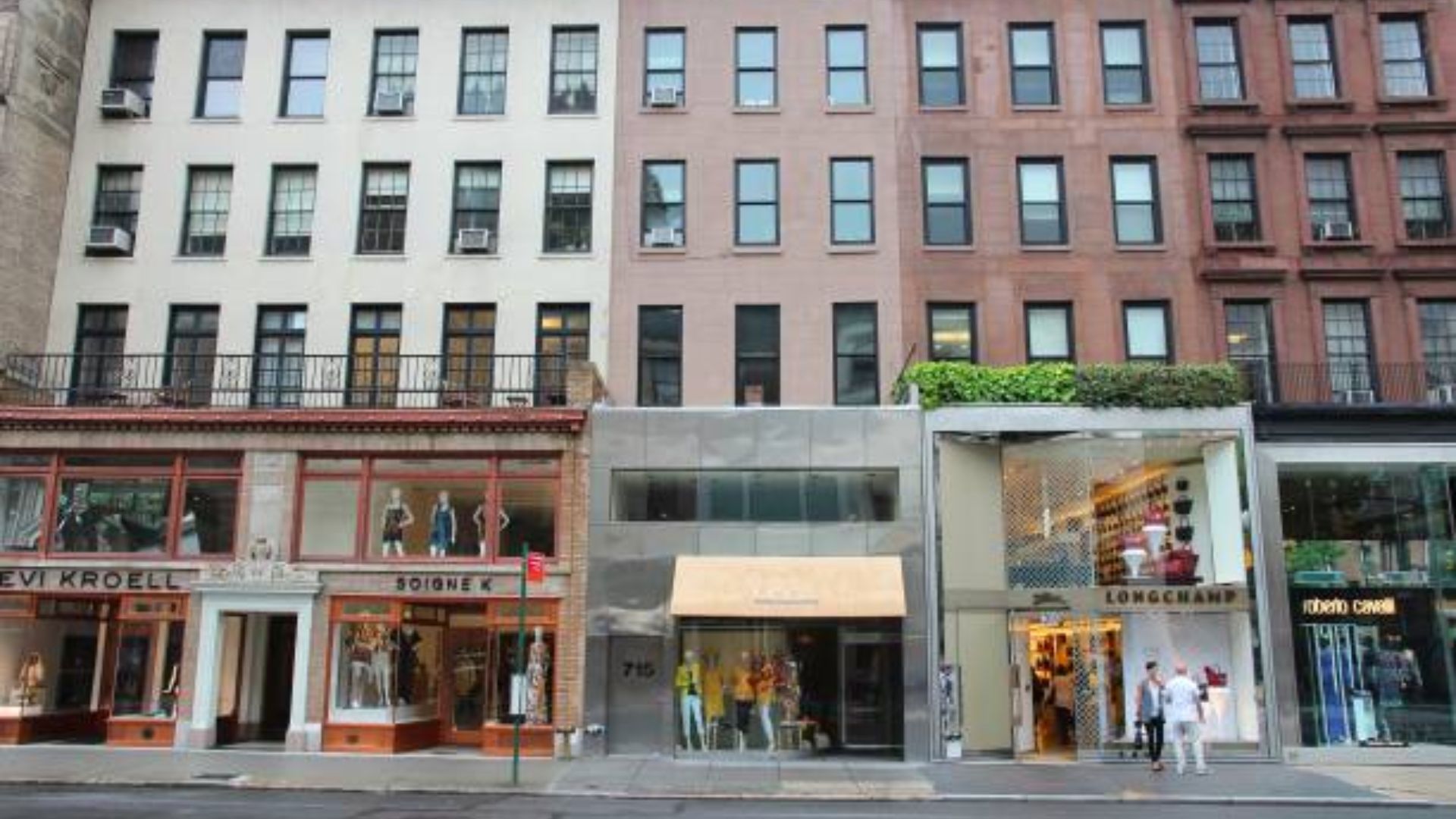 A group of buildings with people walking along the sidewalk, showcasing urban life and activity.