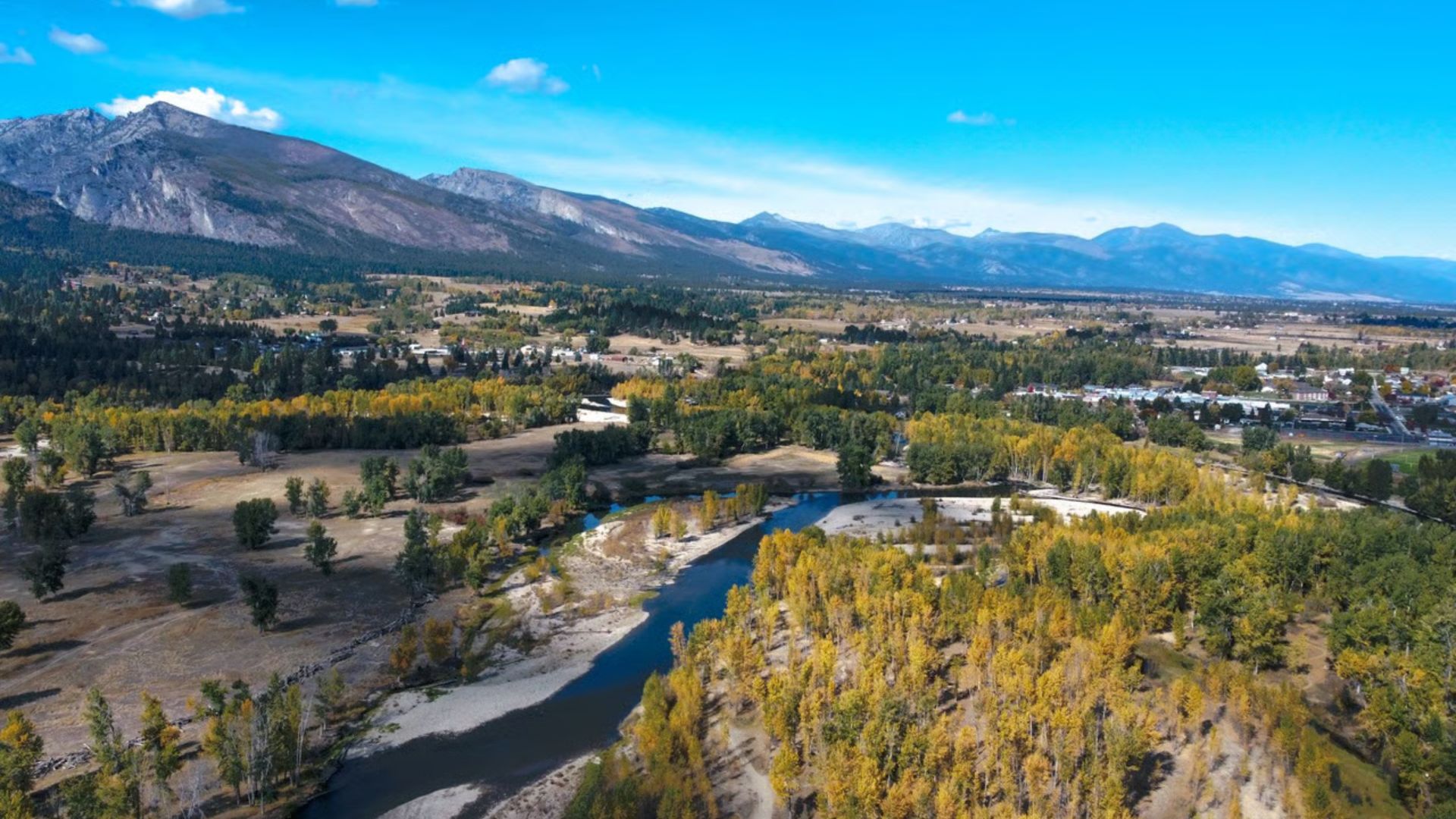 Aerial view of Banff, Alberta, showcasing the town's layout surrounded by mountains and lush greenery.