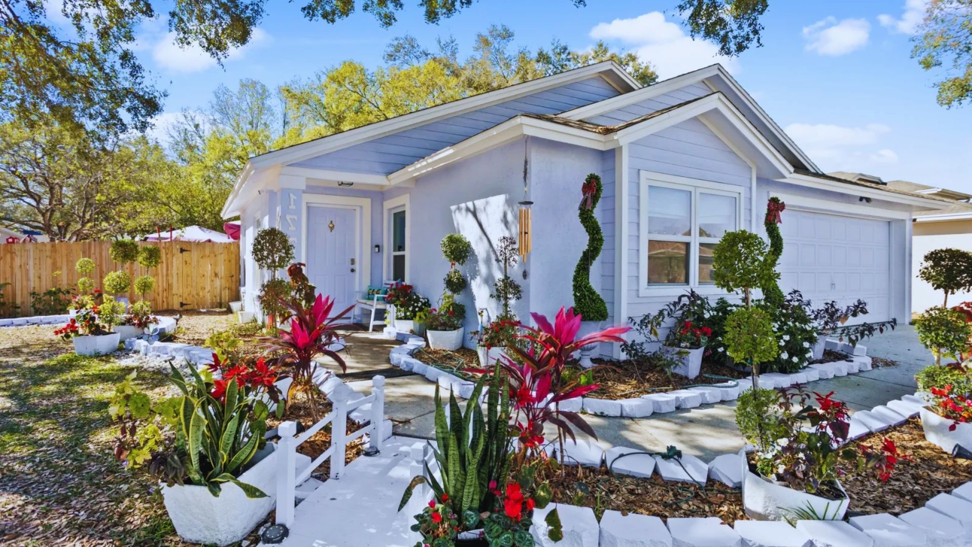 A charming home surrounded by vibrant flowers and lush plants in the yard, creating a welcoming outdoor space.
