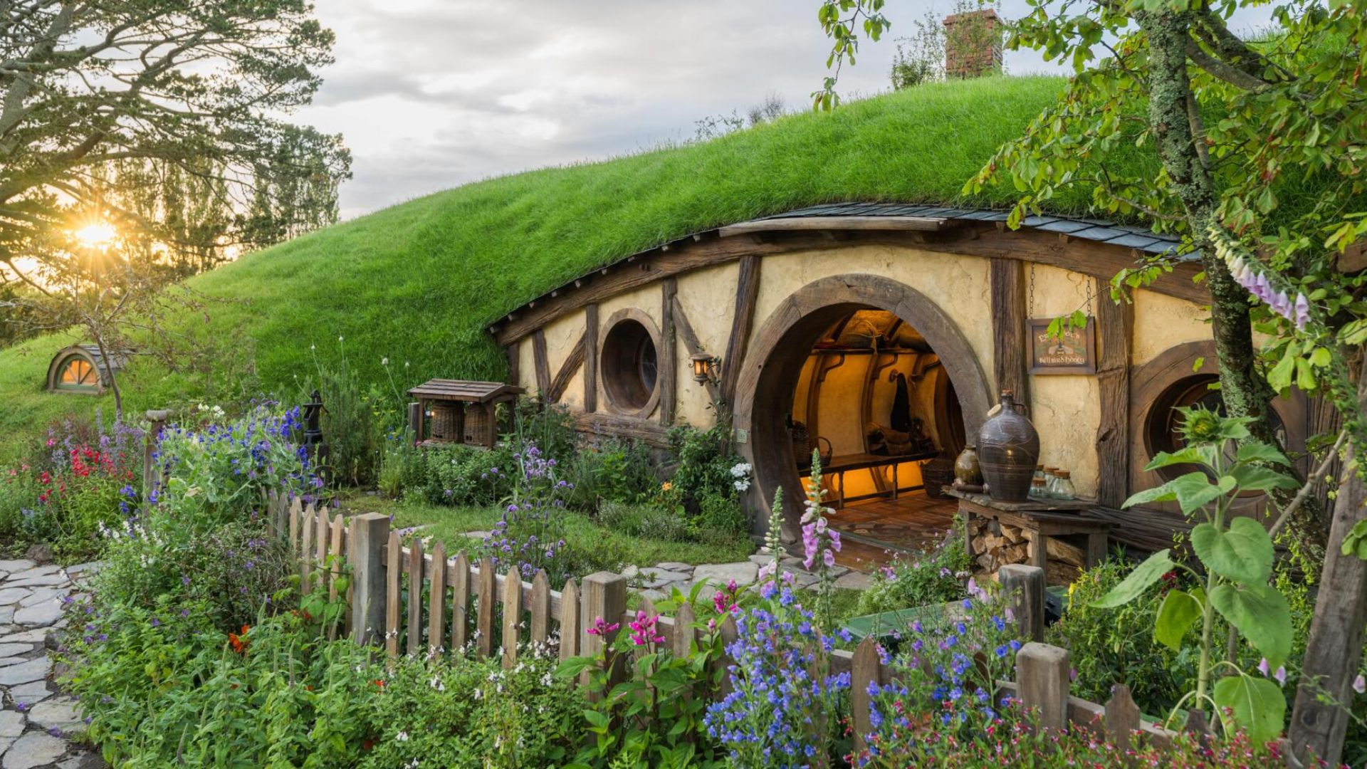 A charming hobbit house nestled among vibrant flowers and lush green grass.