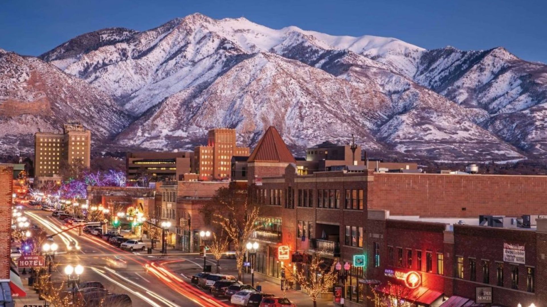 Scenic view of a mountain town, showcasing charming buildings nestled among lush green hills and towering peaks.