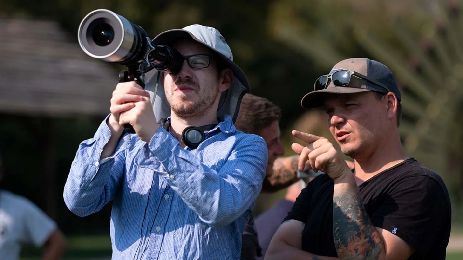 One man points while two others hold a camera, suggesting a collaborative effort in capturing an image.