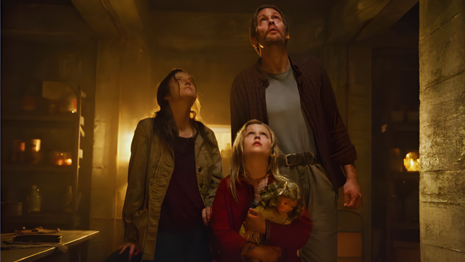 A family stands together in a dimly lit room adorned with flickering candles, creating a warm and inviting atmosphere.
