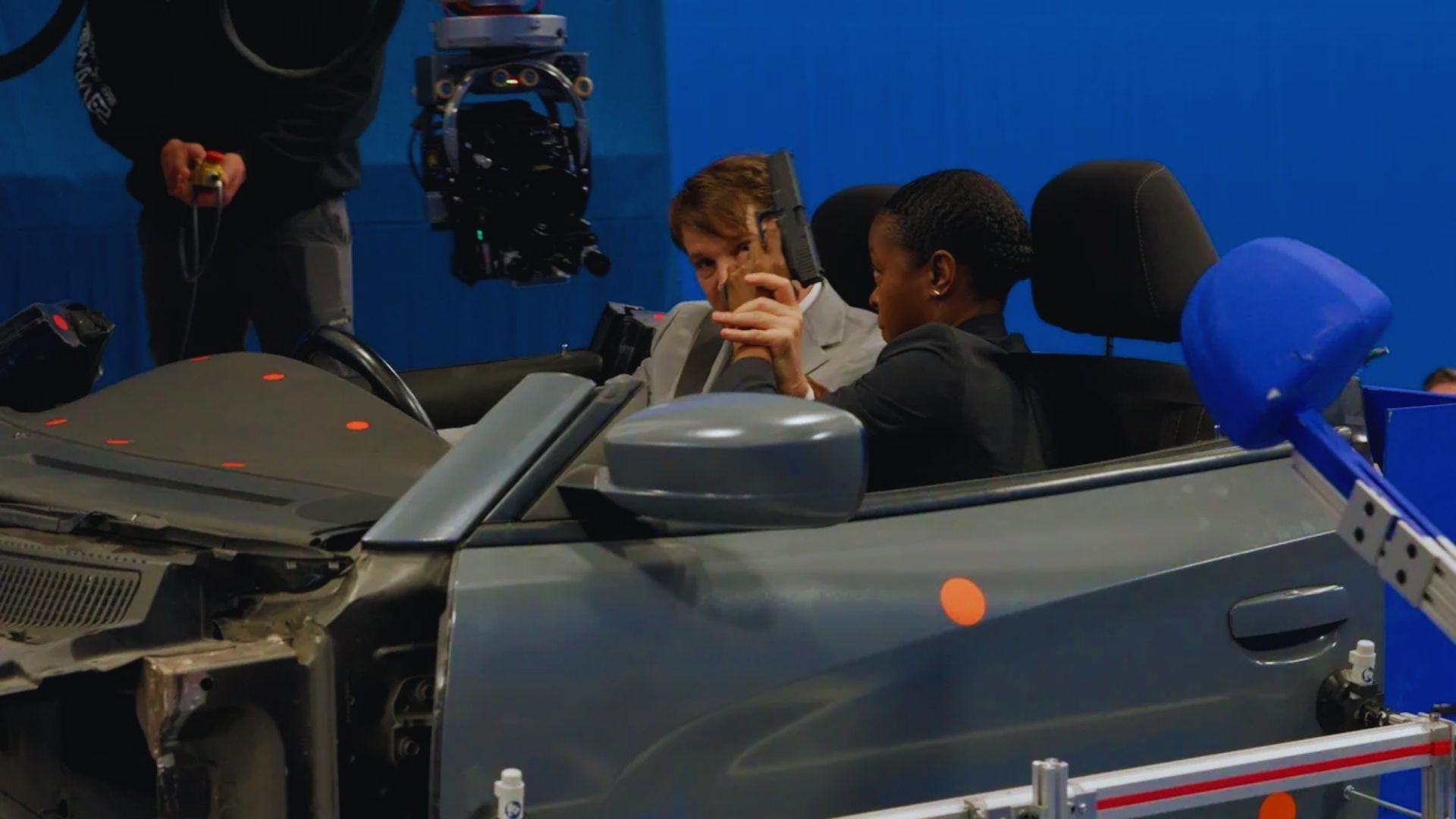 A man sitting in the driver's seat of a car, looking straight ahead with a serious expression.