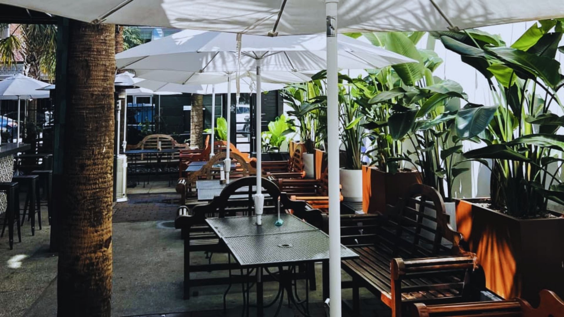A restaurant patio featuring tables and chairs arranged under colorful umbrellas for outdoor dining.