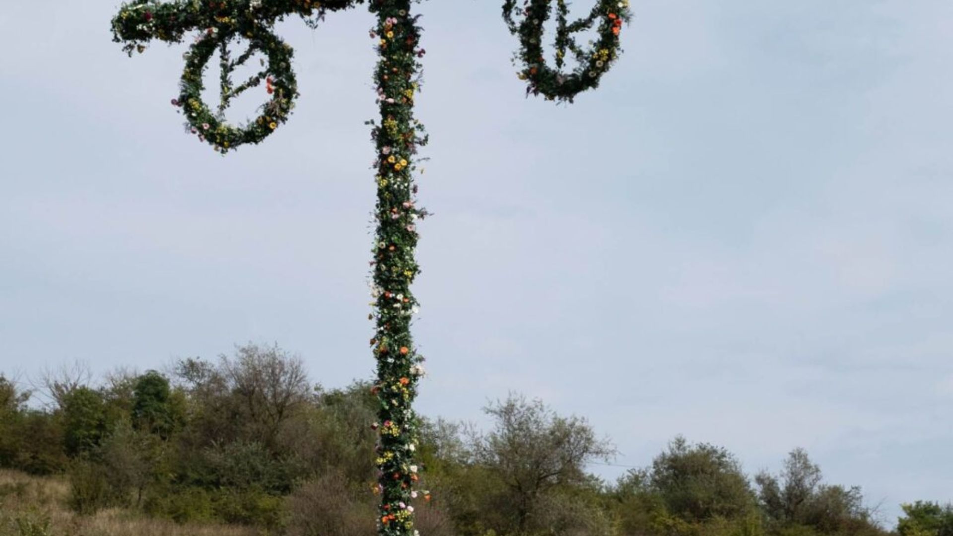 A large sign adorned with colorful flowers, prominently displayed in a garden setting.