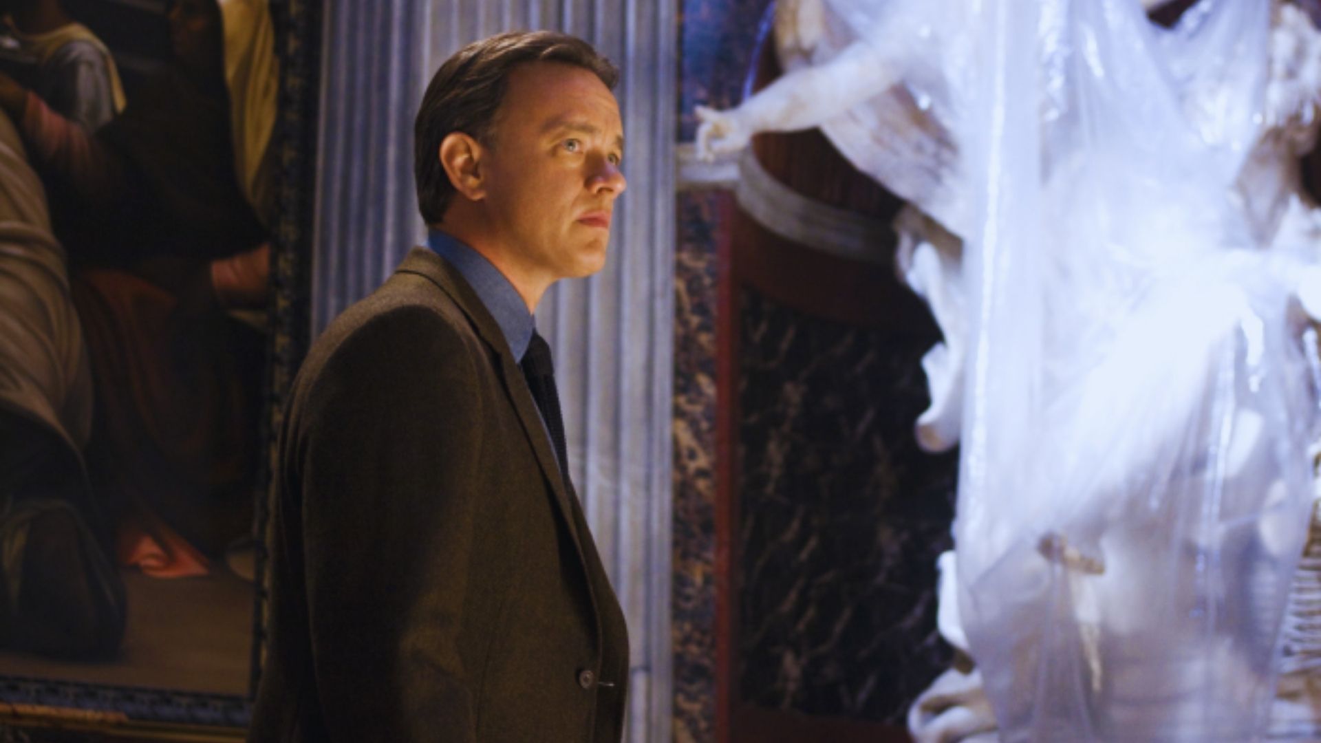 A man in a suit and tie stands confidently in front of a large statue, showcasing a blend of professionalism and art.