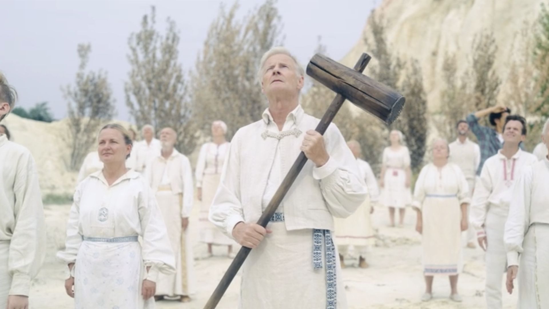 Several people in white attire, collectively holding axes, posing together in a display of solidarity.
