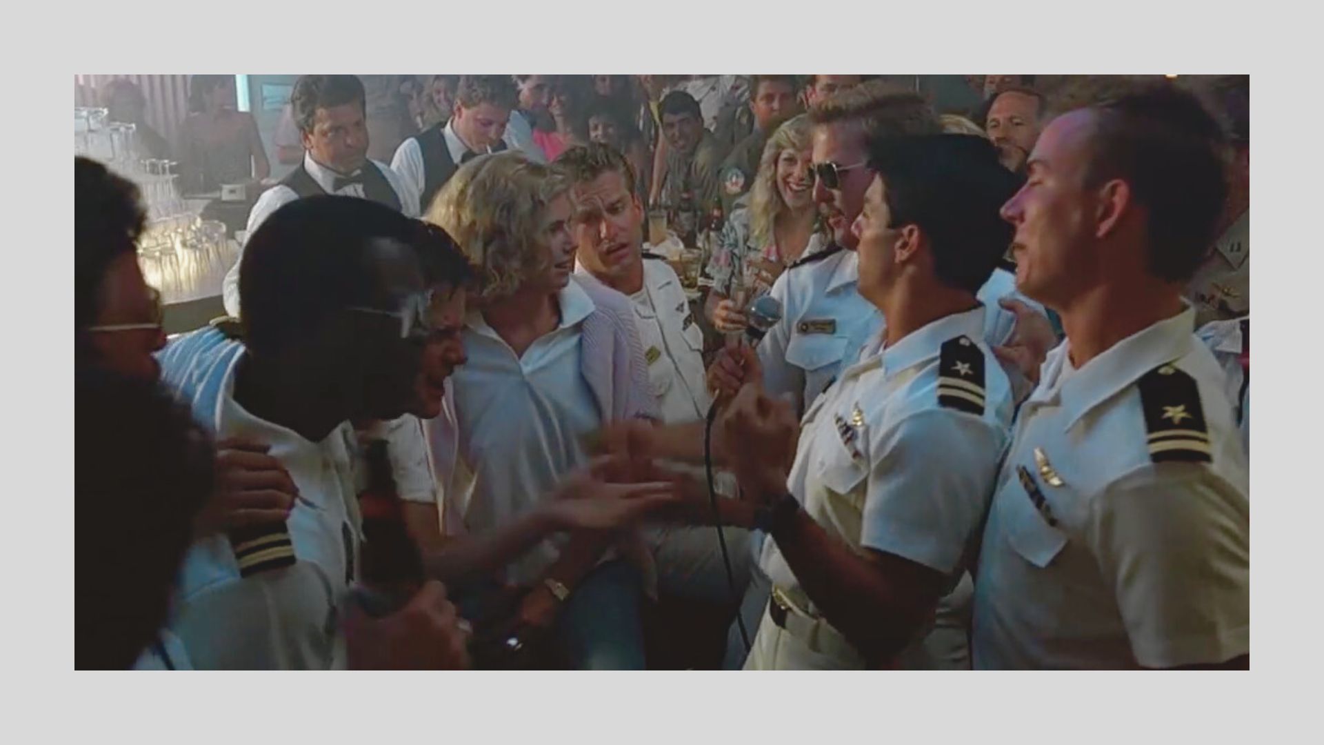 A lively bar scene with people in naval uniforms singing enthusiastically, holding microphones. A cheerful crowd surrounds them, creating a festive atmosphere.