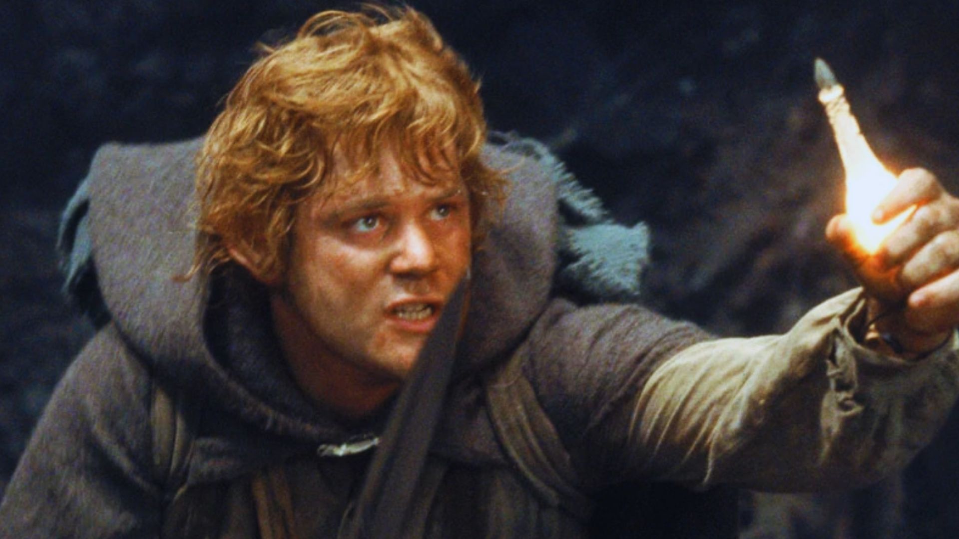 A determined character with tousled hair, clad in a cloak, holds up a bright light in a dark setting, conveying urgency and resolve.