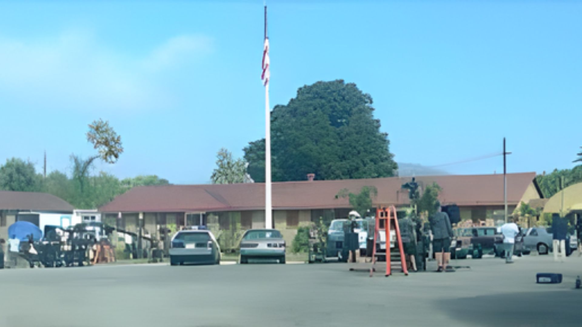 People standing near a flagpole outside a house at Santa Clarita Studios, the primary filming site for NCIS.