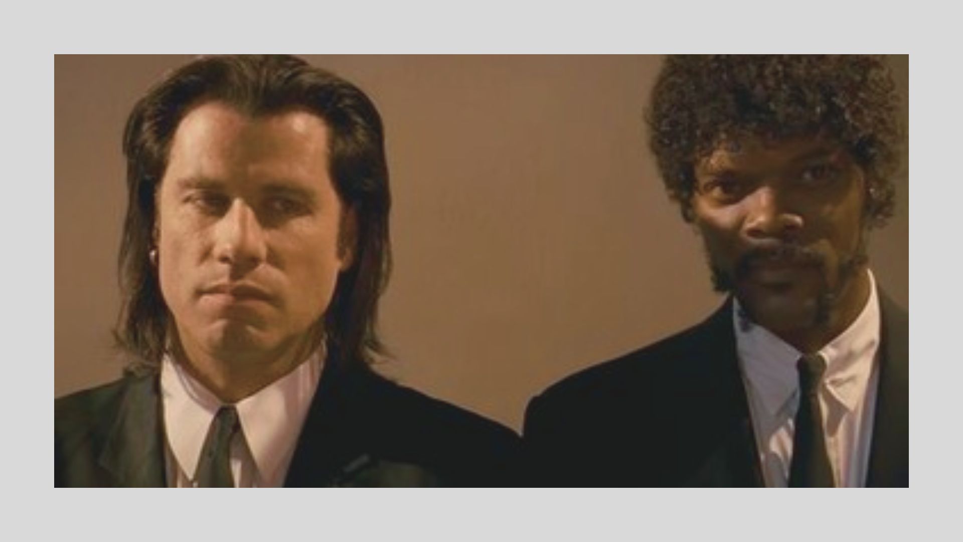 Two men in dark suits stand side by side against a neutral background. They convey a serious expression, dressed formally with narrow ties, evoking a tense mood.