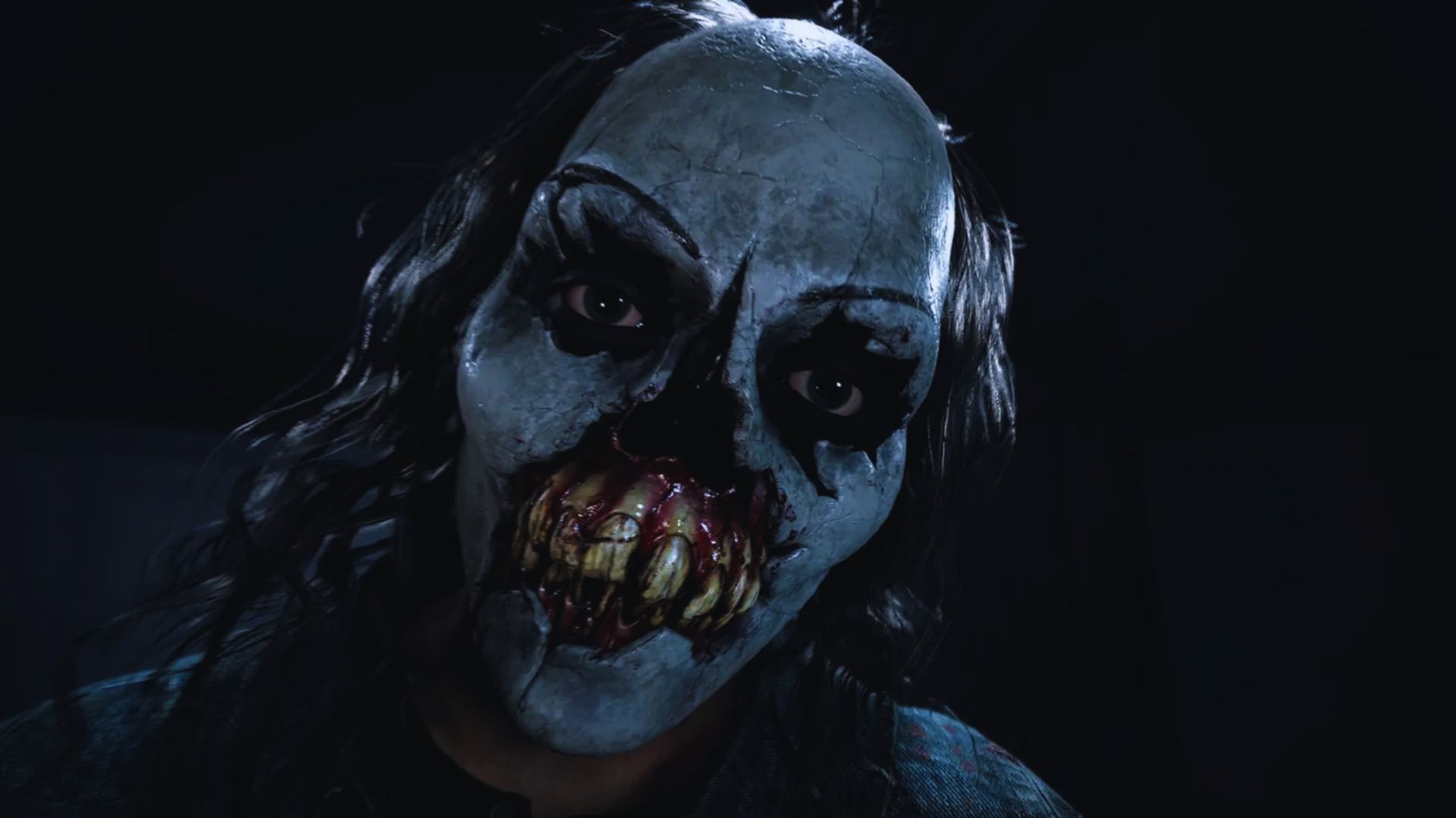 Creepy figure in a dark setting with a grotesque painted mask, featuring hollow eyes and jagged teeth. The eerie atmosphere conveys horror and dread.