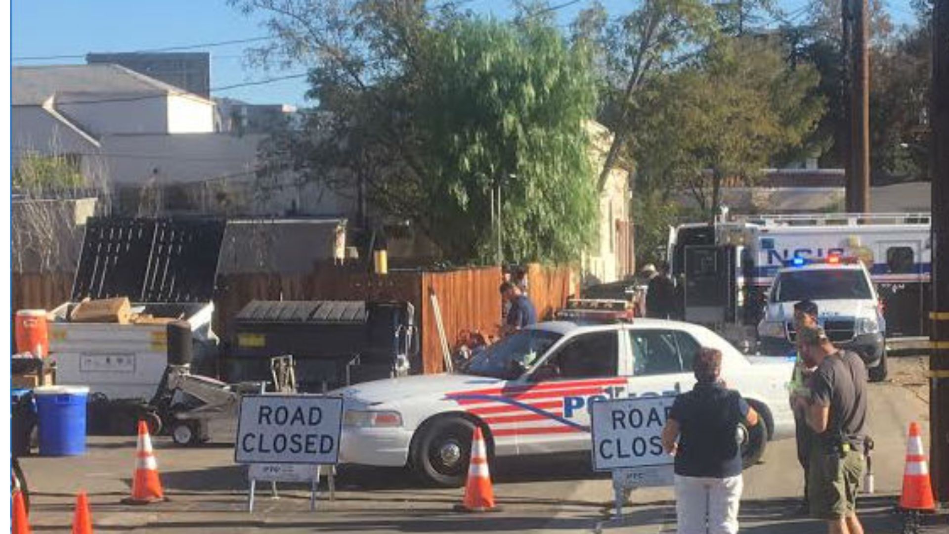 A row of police cars and traffic cones is set up in front of a building in Valencia, California, for a filming location
