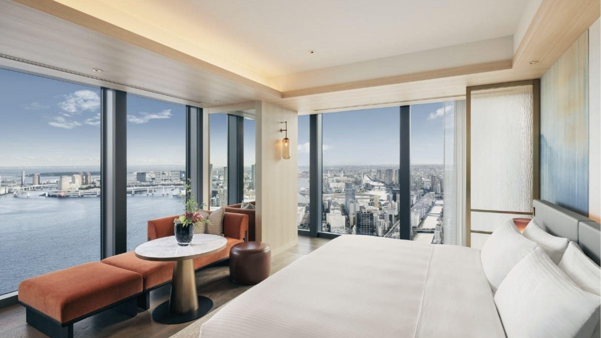High-rise hotel room with floor-to-ceiling windows overlooking Tokyo Bay and the city skyline.