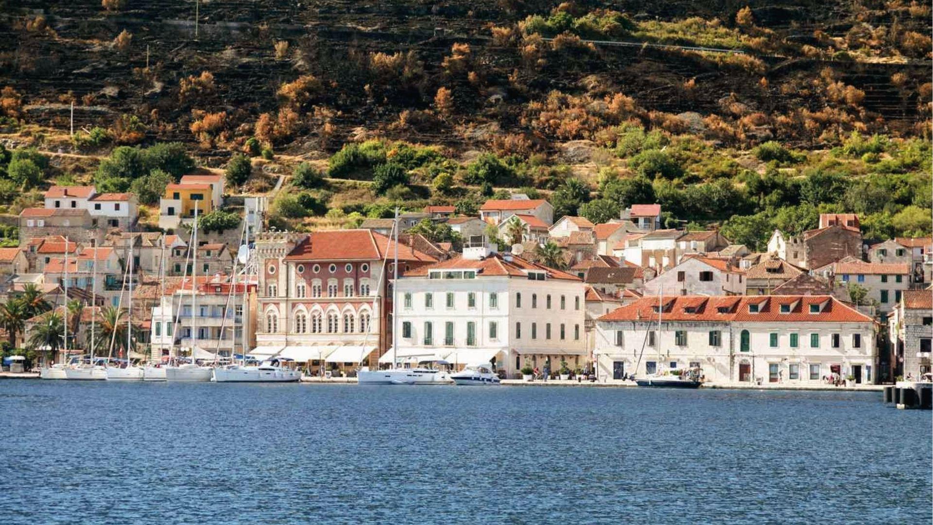 Waterfront of Vis town with sailboats and stone buildings, used as Kalokairi port in Mamma Mia 2.