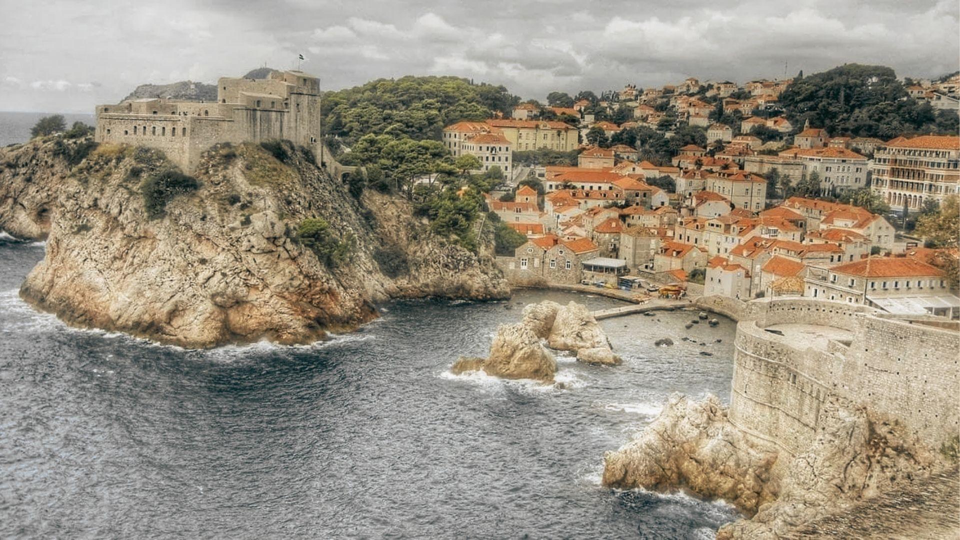 Stone fortress on a rocky outcrop overlooking Dubrovnik’s West Harbour and red-roofed buildings.