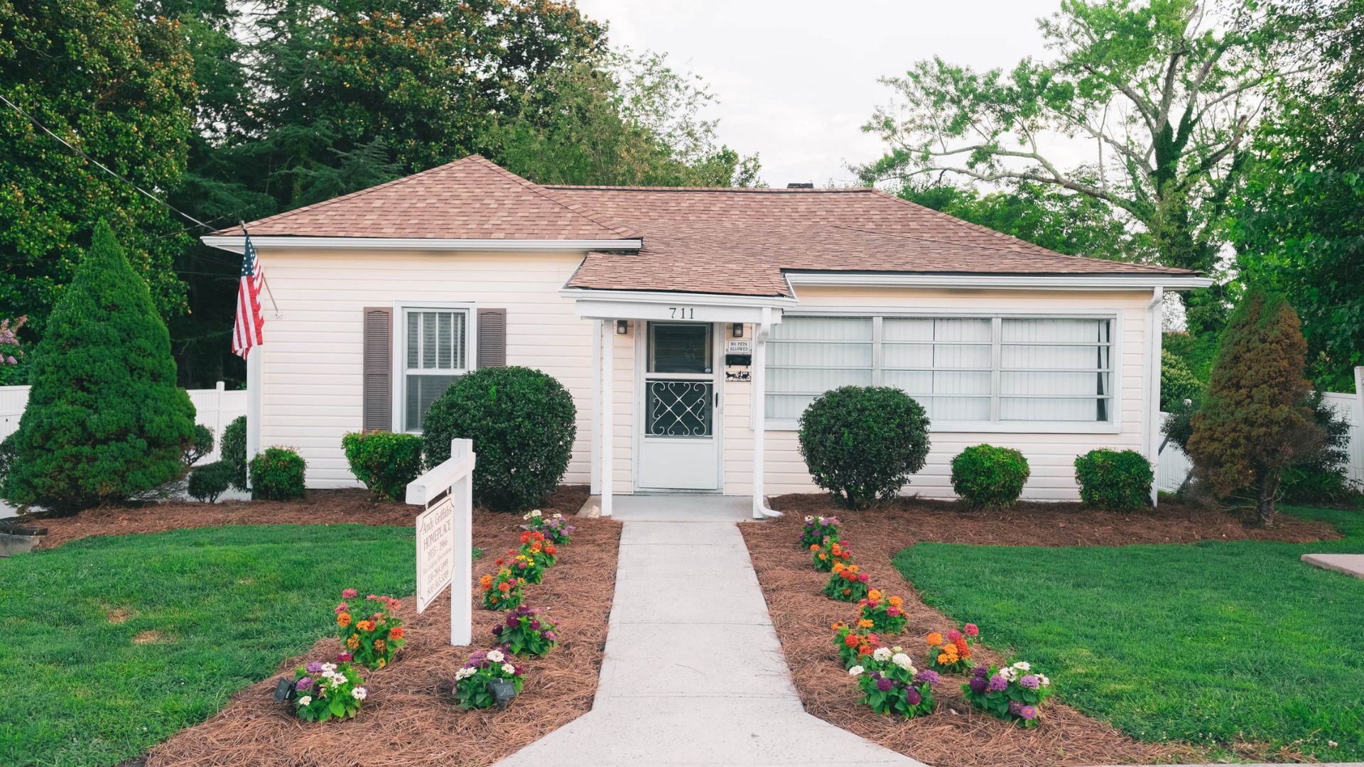 A white single-story house with a red roof and flower-lined walkway in Mount Airy, North Carolina.