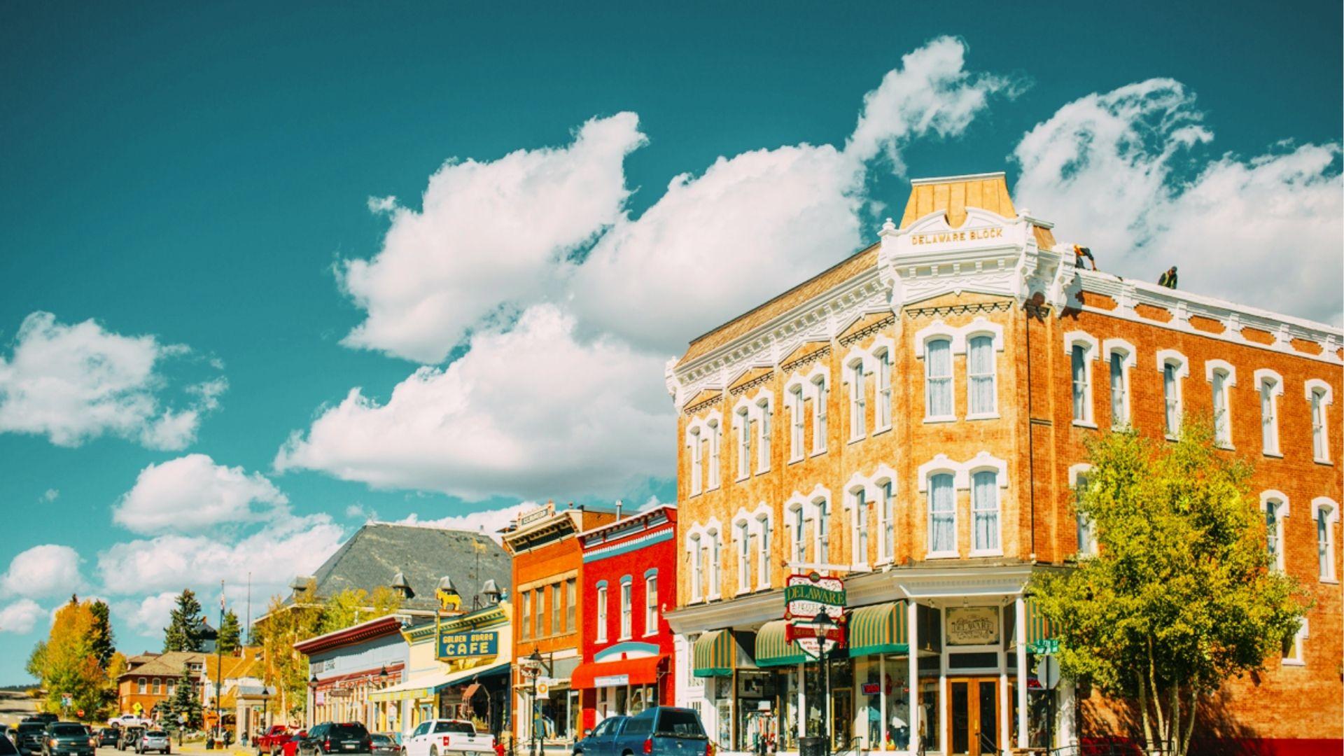 Colorful historic downtown street with Delaware Block building, shops, parked cars, and blue sky