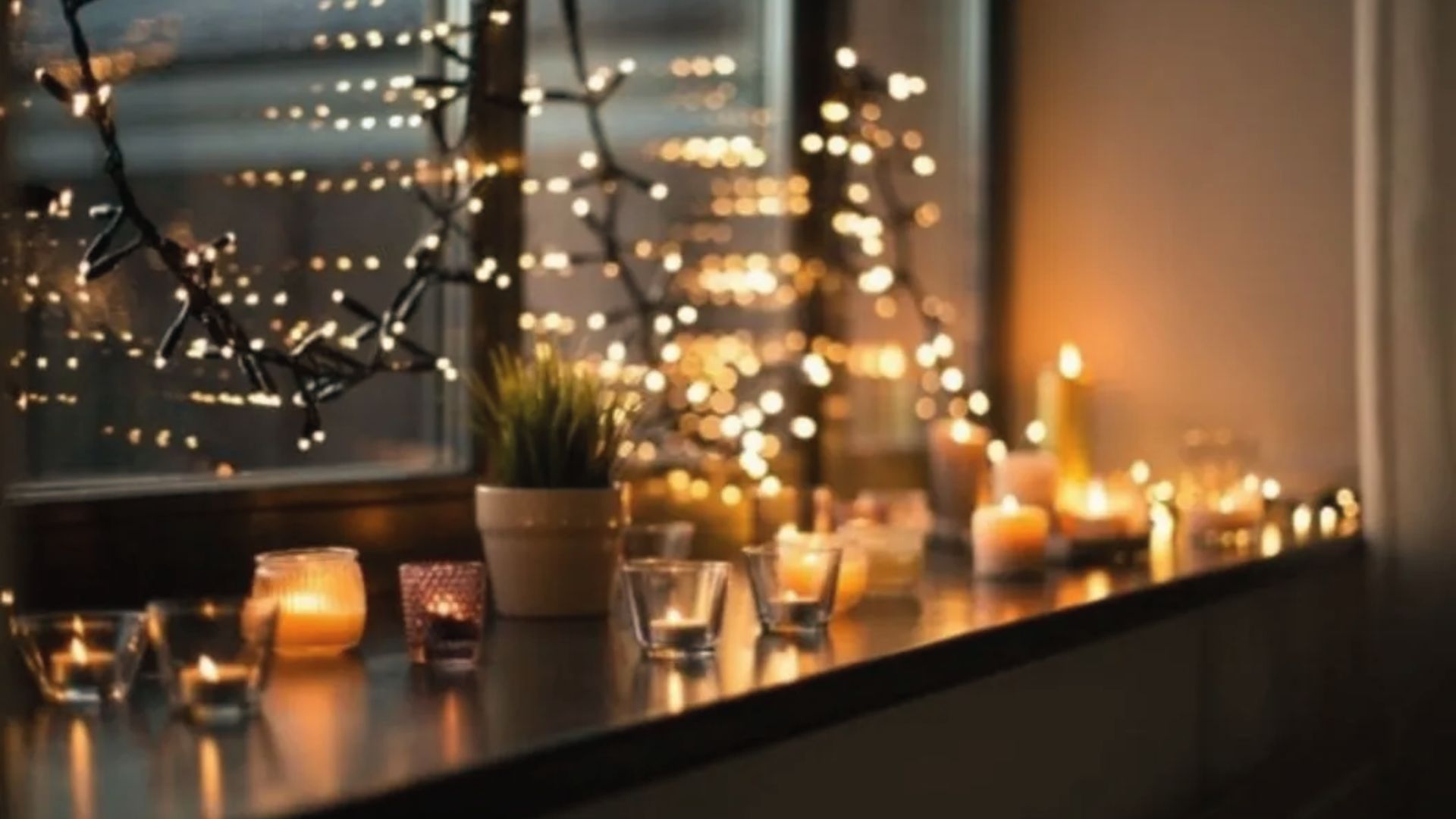 A small potted plant sits among the candles, creating an intimate vibe for a home movie night.