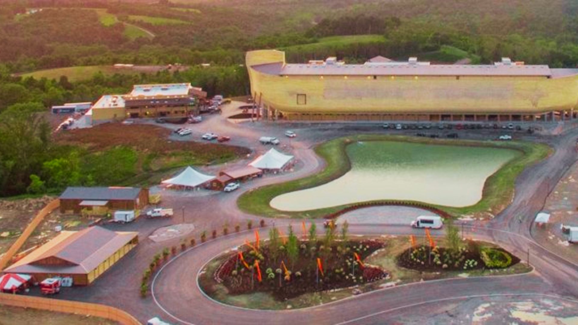 Aerial view of the Ark Encounter at sunset, showing the 510-foot-long Noah’s Ark replica beside a pond and visitor center.