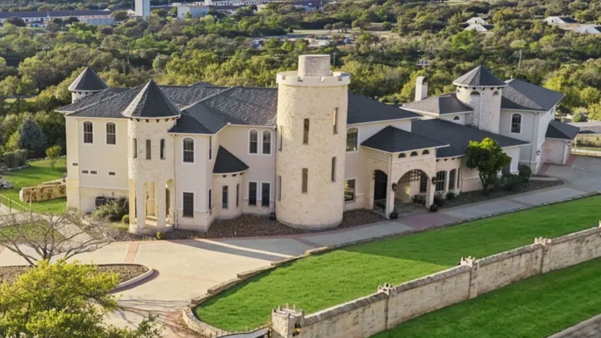 Aerial view of a large stone mansion with turrets and dark roofs used as Demented Hills Asylum.