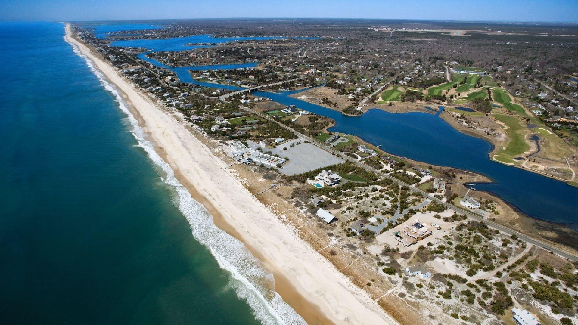 Aerial view of an upscale beach town with white sand, luxury homes, and winding blue waterways.