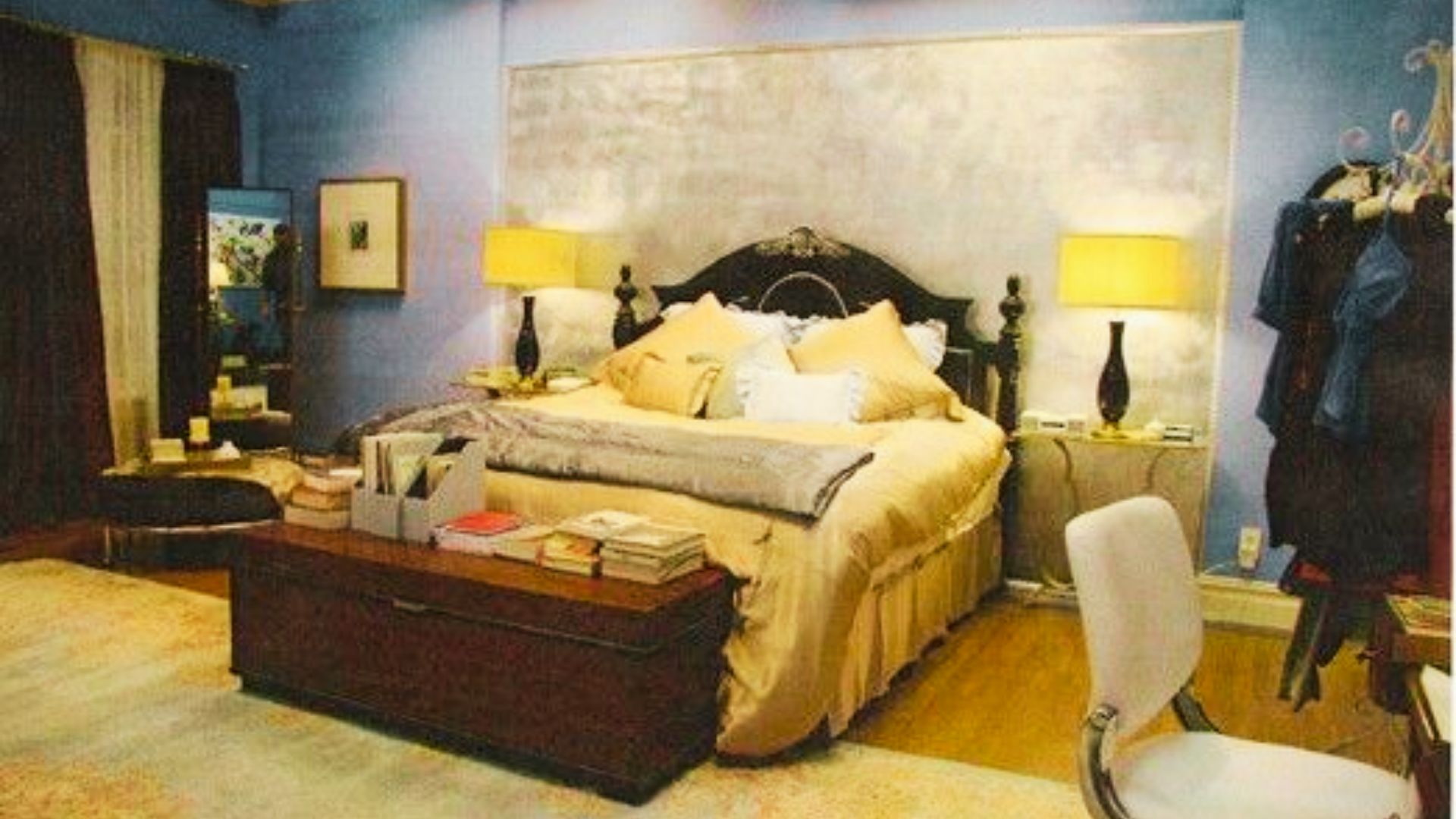 Full view of Blair Waldorf’s blue-walled bedroom with dark wood bed, gold comforter, and matching nightstands.