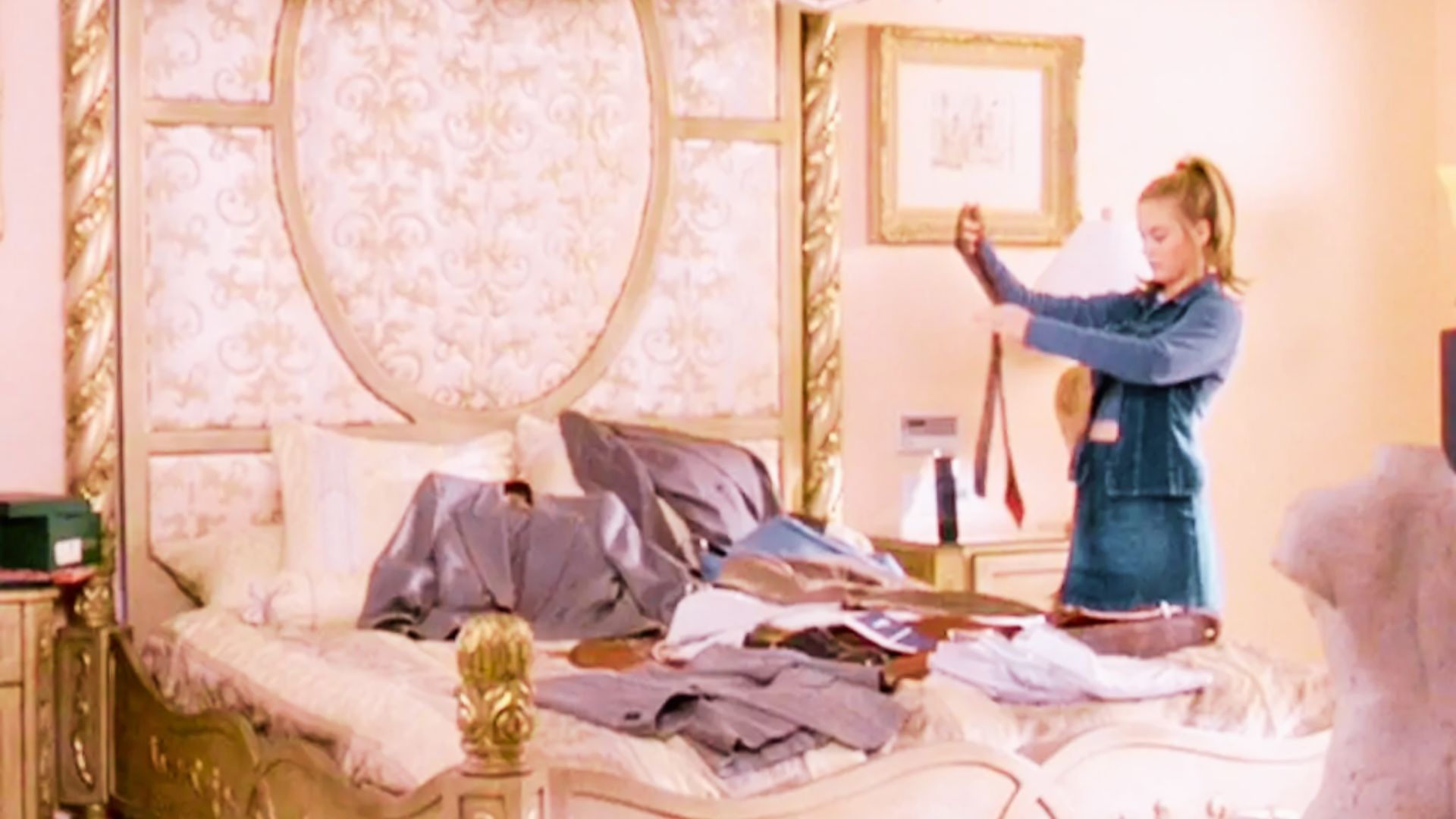 A corner of Blair Waldorf’s bedroom with a brown tufted chaise lounge, framed Audrey Hepburn portrait, and ivory drapes.
