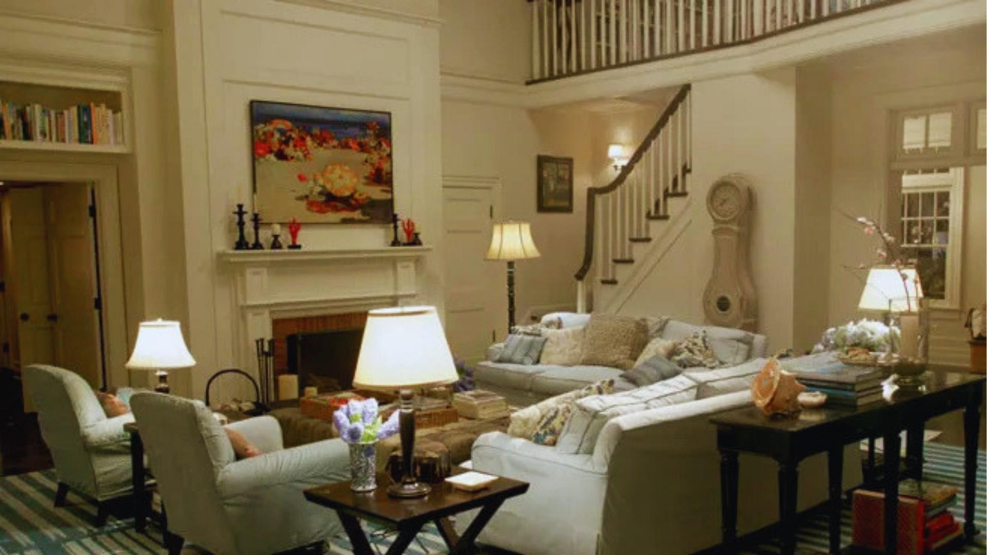 Something's Gotta Give living room featuring white slipcovered sofas, blue striped rug, fireplace, beach art, and Mora clock.