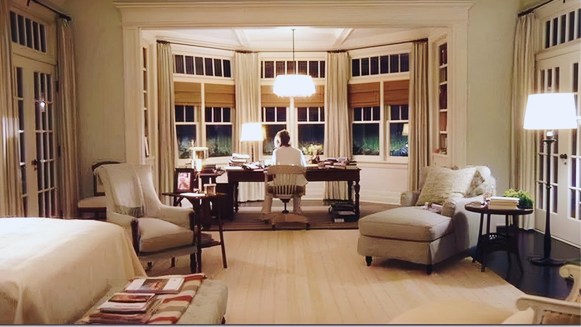 Erica's bedroom study in Something's Gotta Give with bay window, dark wood desk, and cream slipcovered chairs in warm lighting.