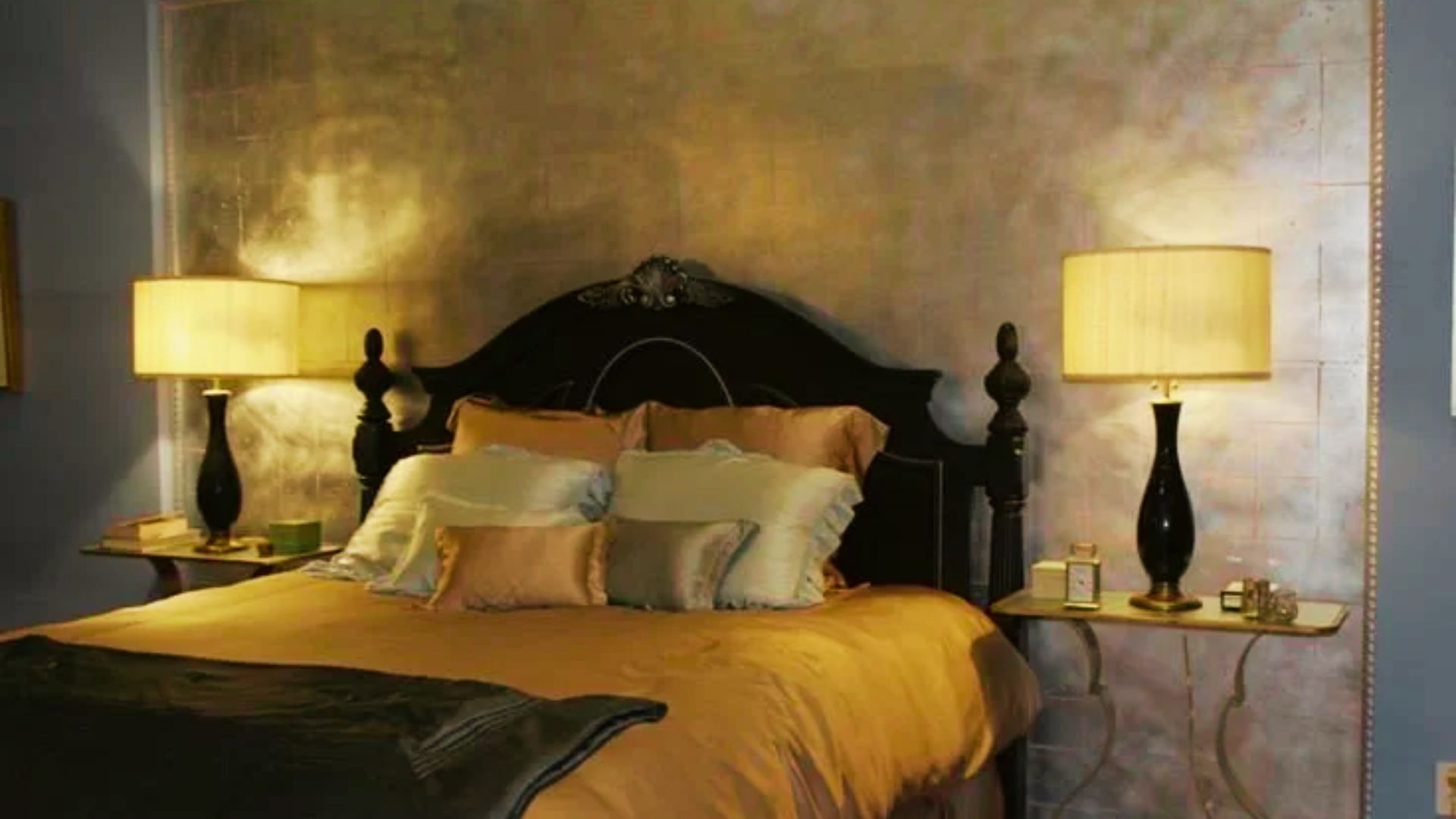 Blair Waldorf’s iconic Upper East Side bedroom featuring a dark wood headboard, gold silk bedding, and matching black table lamps.
