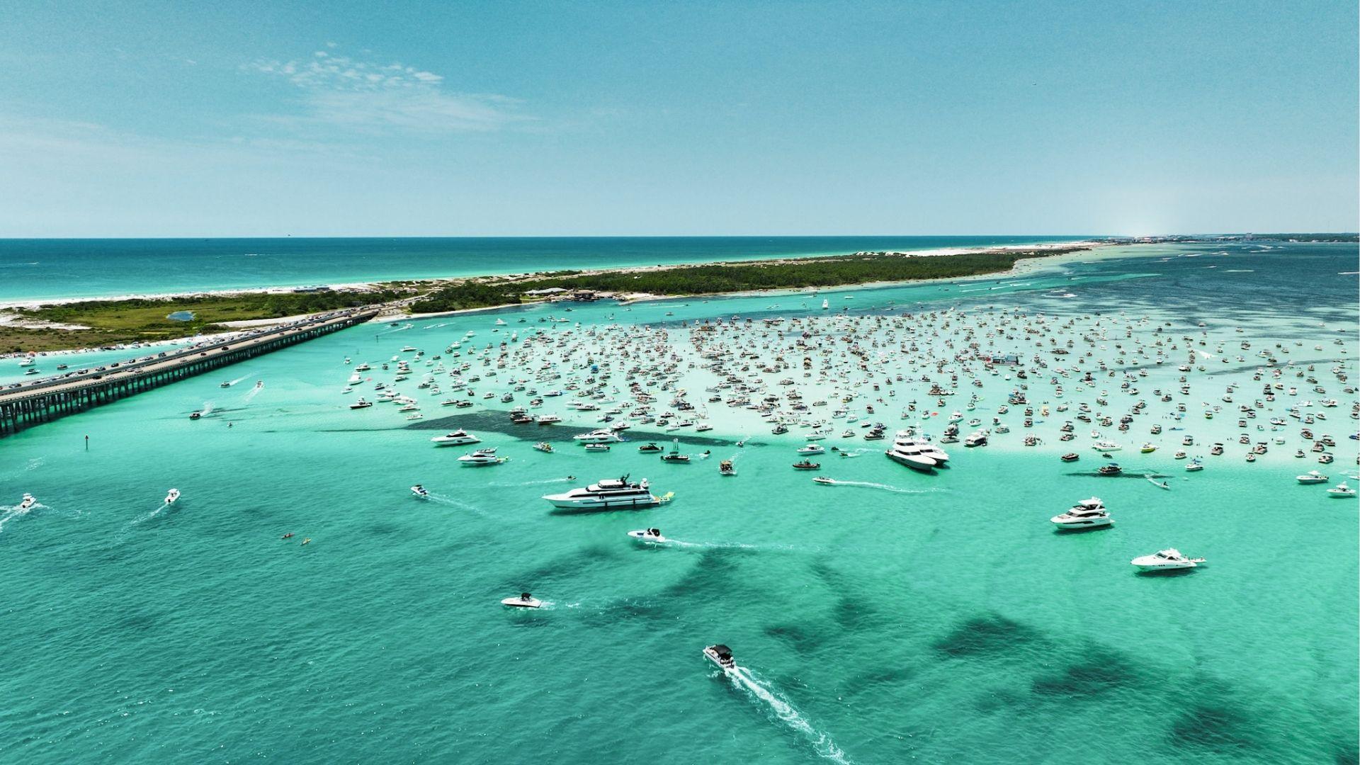 Turquoise bay filled with hundreds of boats and yachts near bridge and white sandy beaches