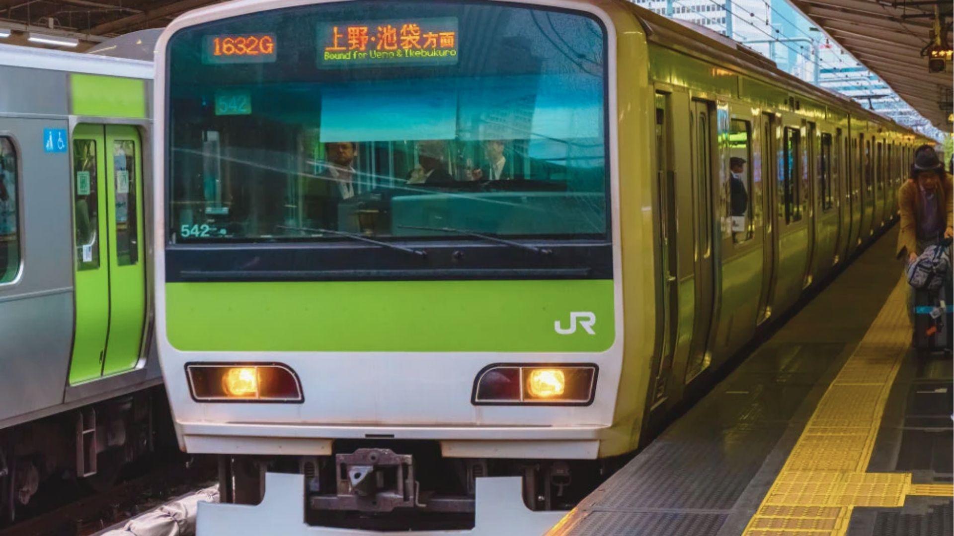 Green-striped JR Yamanote train bound for Ueno and Ikebukuro waiting at a Tokyo station platform.