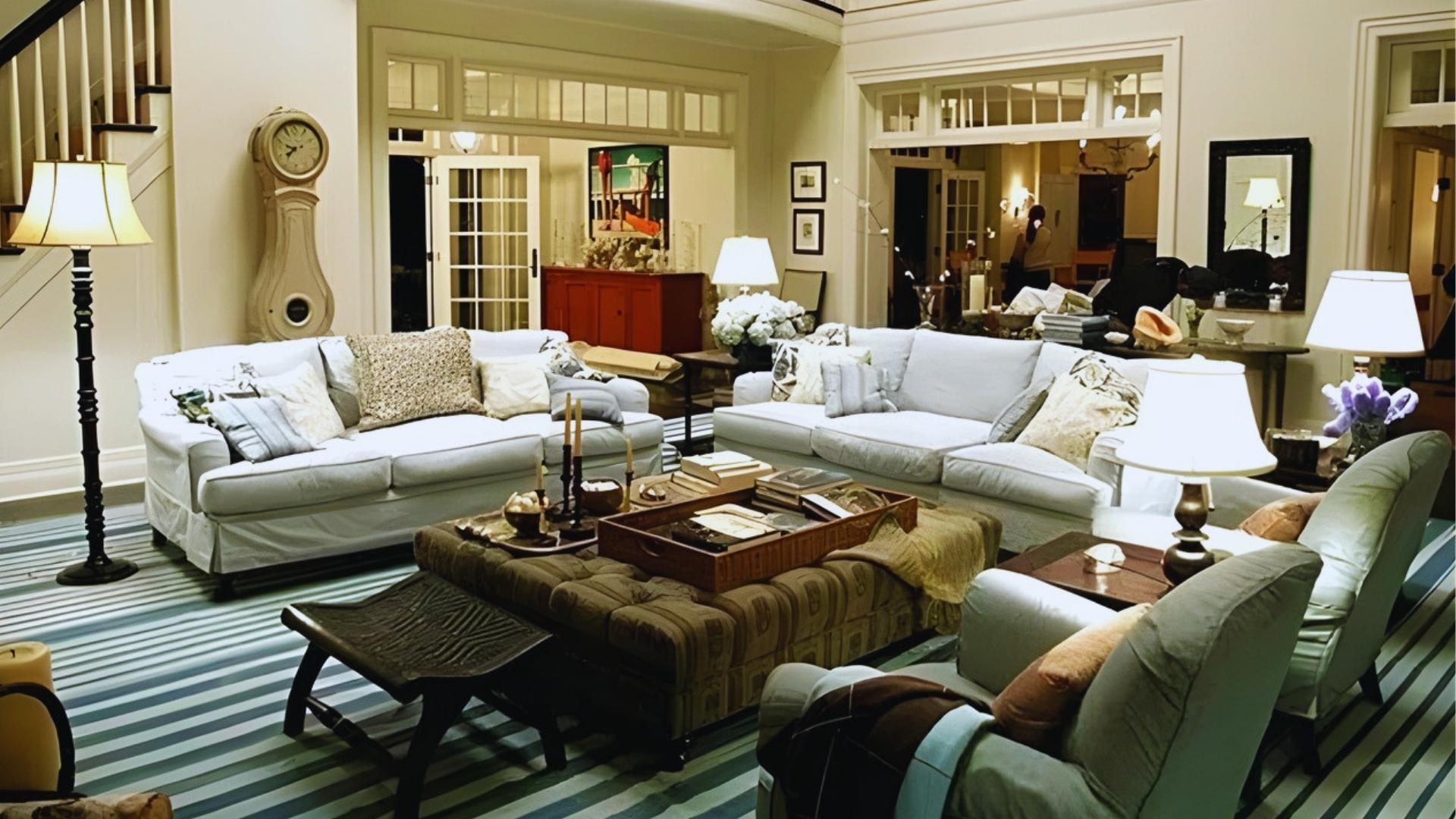 Hamptons living room from Something's Gotta Give with white sofas, tufted ottoman, table lamps, and French doors to the dining room.