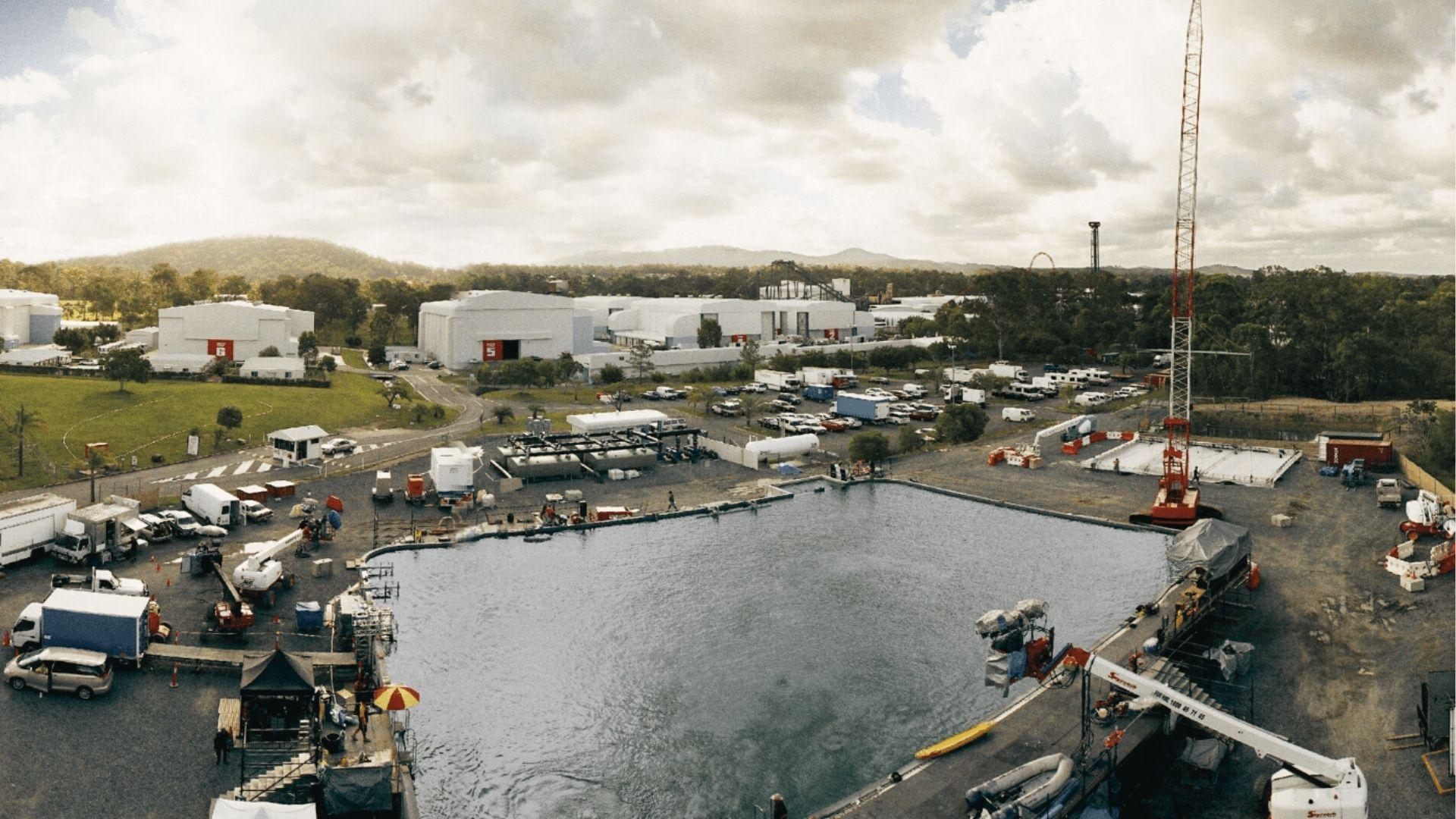 Aerial of the massive outdoor water tank at Village Roadshow Studios, Gold Coast, surrounded by production trucks.