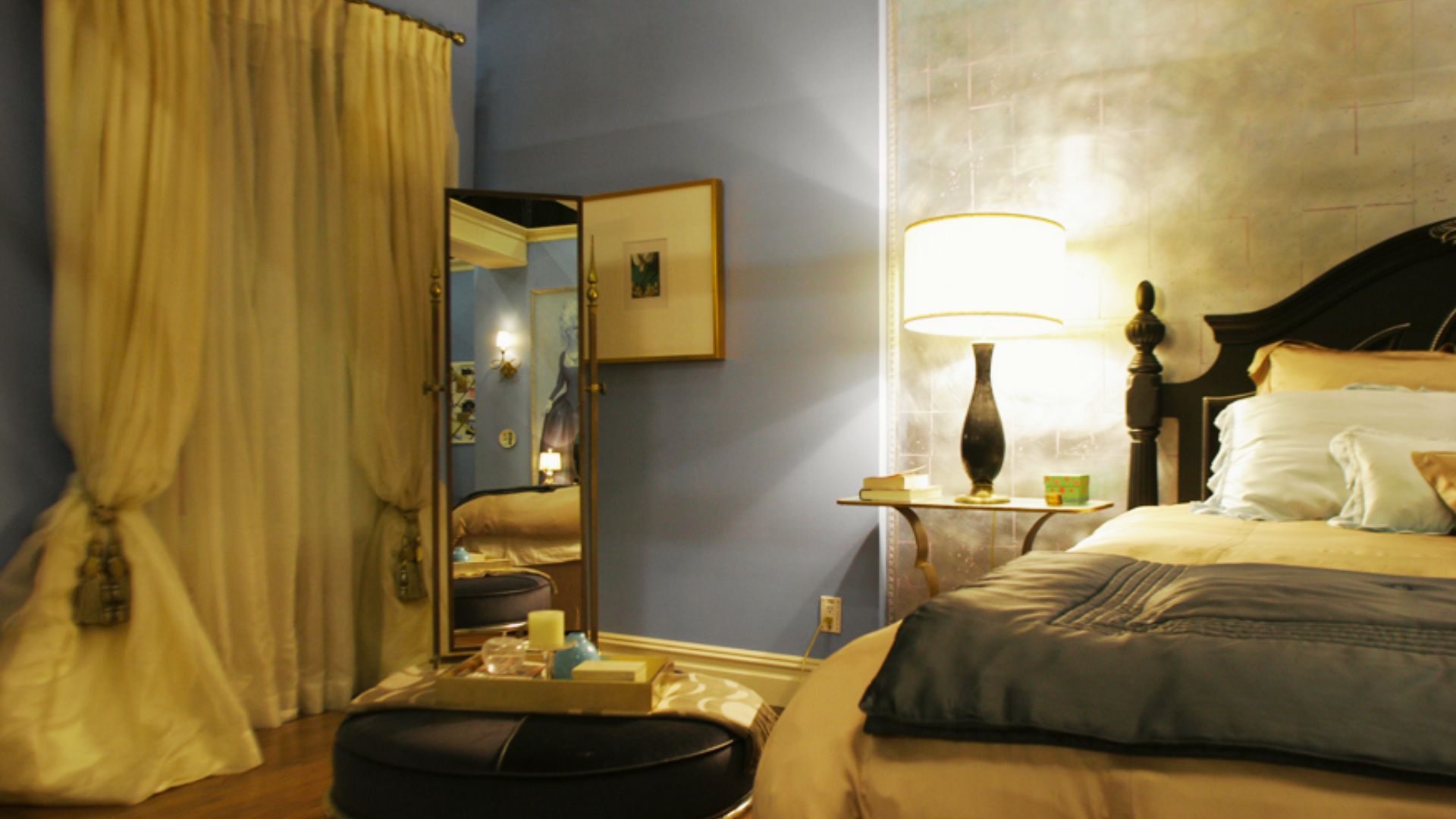 Blair’s bedroom corner showing a tall tri-fold mirror, sheer ivory curtains, and blue walls.