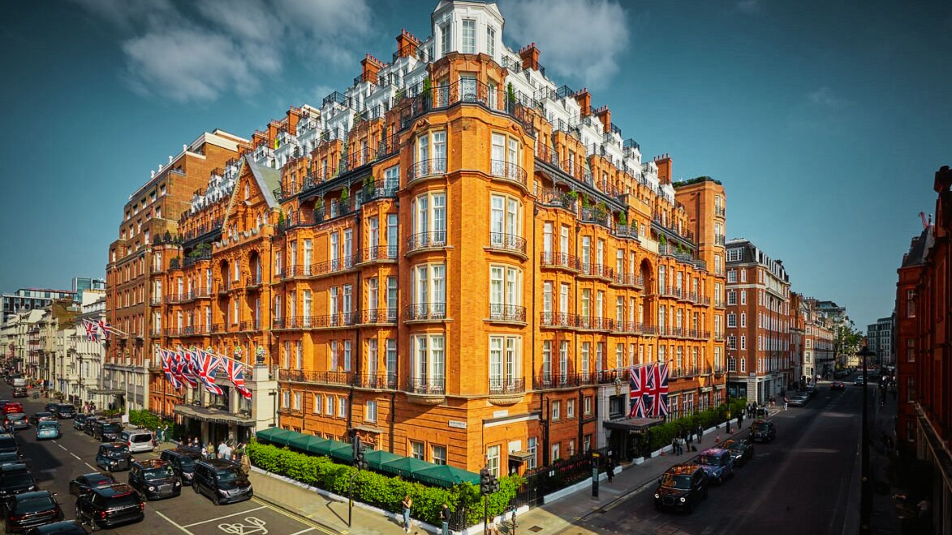 Grand red-brick hotel Mayfair with Union Jack flags in Kensington offers upscale stays near Hyde Park, museums, and luxury shopping.