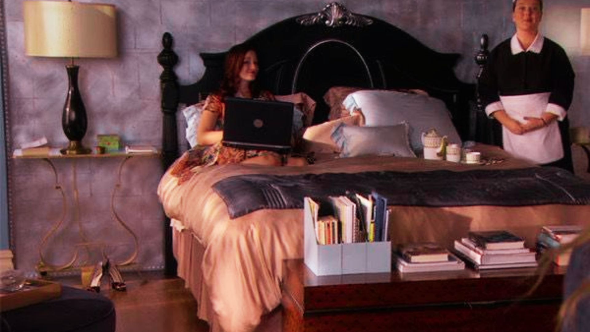 Blair Waldorf works on a laptop in bed while her maid Dorota stands nearby with breakfast in bed.