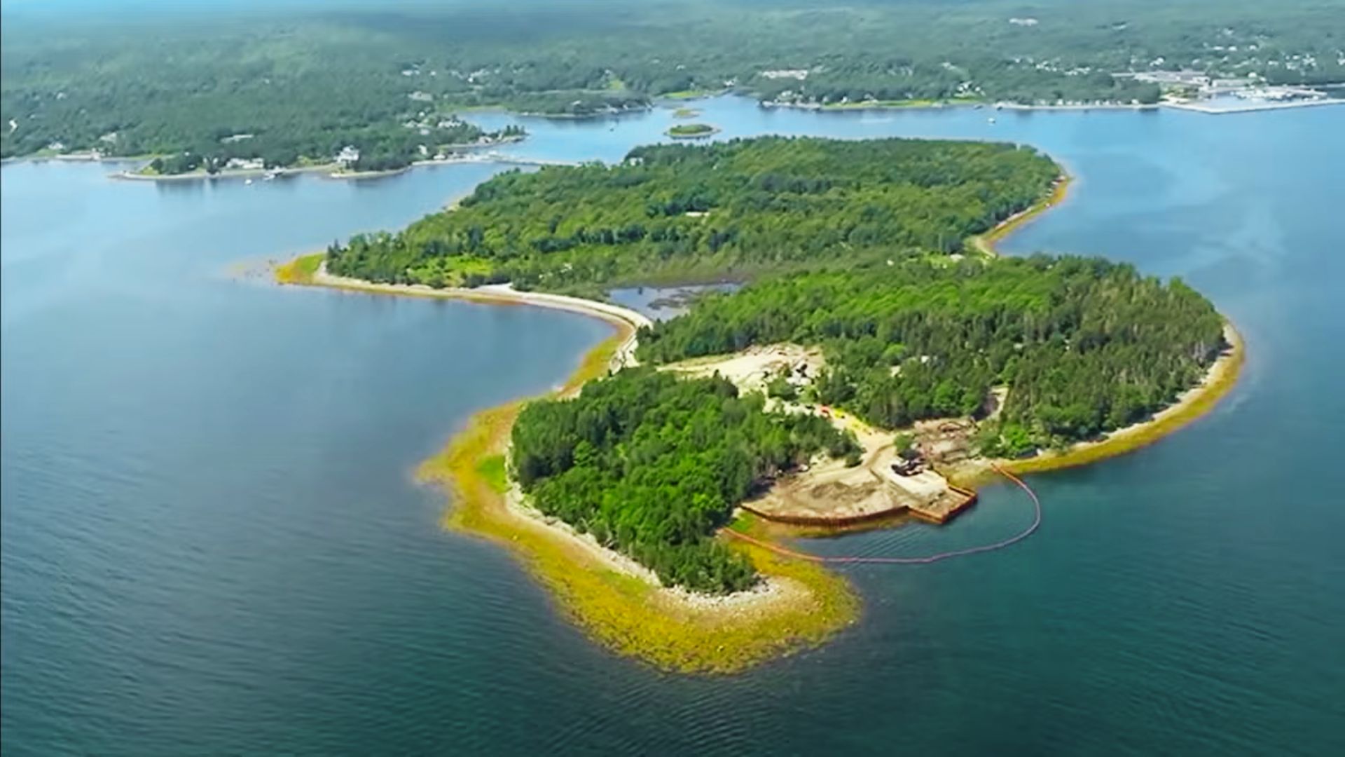 Aerial view of Oak Island showing excavation site, trees, shoreline, and causeway link.