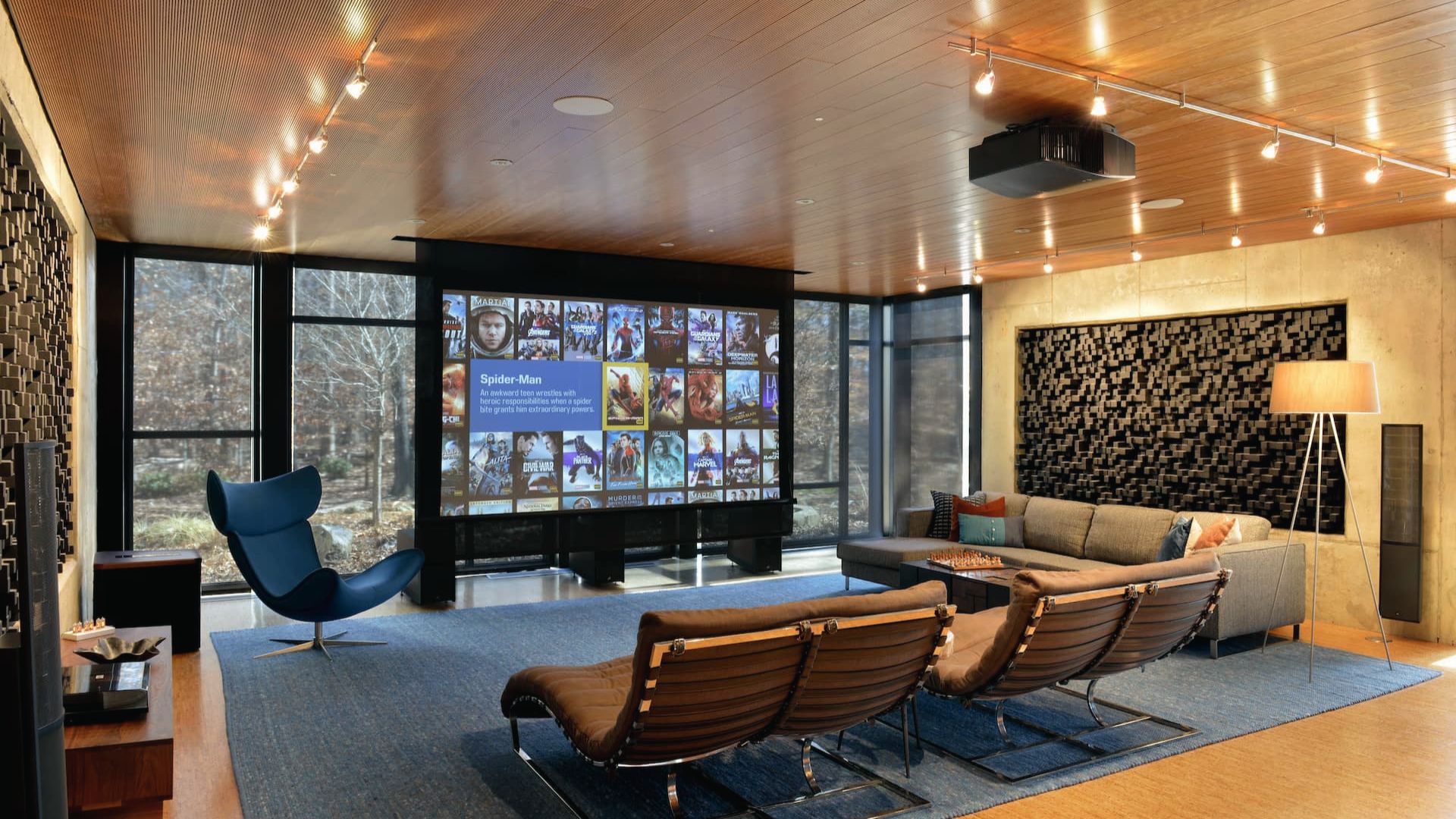 Spacious home theater with a large projection screen displaying movie posters, surrounded by leather recliners